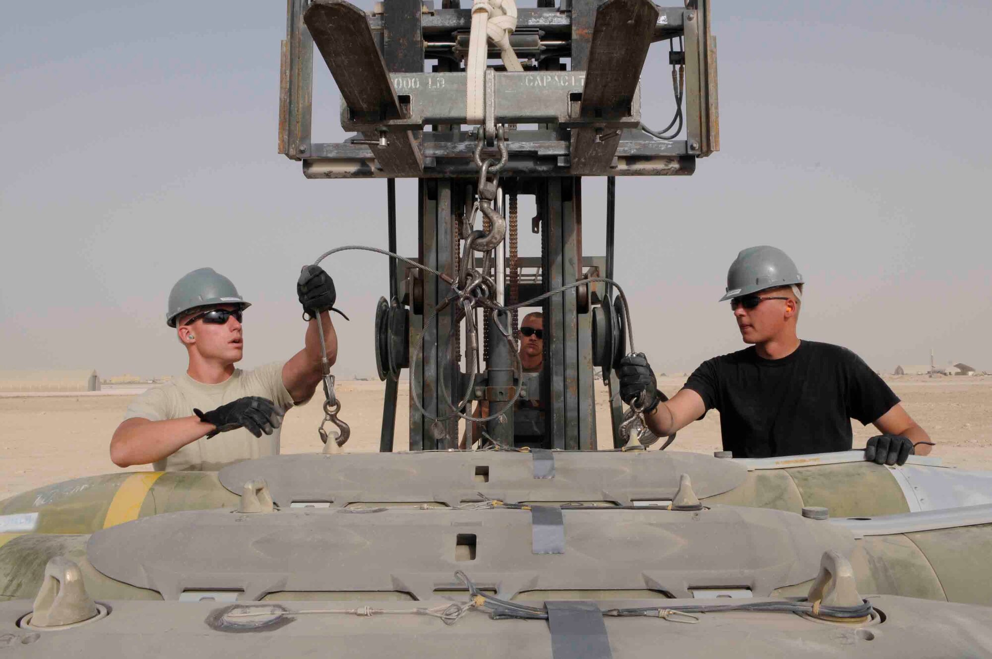 Staff Sgts. Robert Ball (right) and  Daniel Reed (left) prepare to unload a Joint Direct Attack Munition from a munitions handling trailer at a Southwest Asia air base March 18. Maintenance crew load and unload, on average, 50 bombs per week. Bombs weigh approximately 2,000 pounds.  (U.S. Air Force photo/Tech. Sgt. Johnny Saldivar)