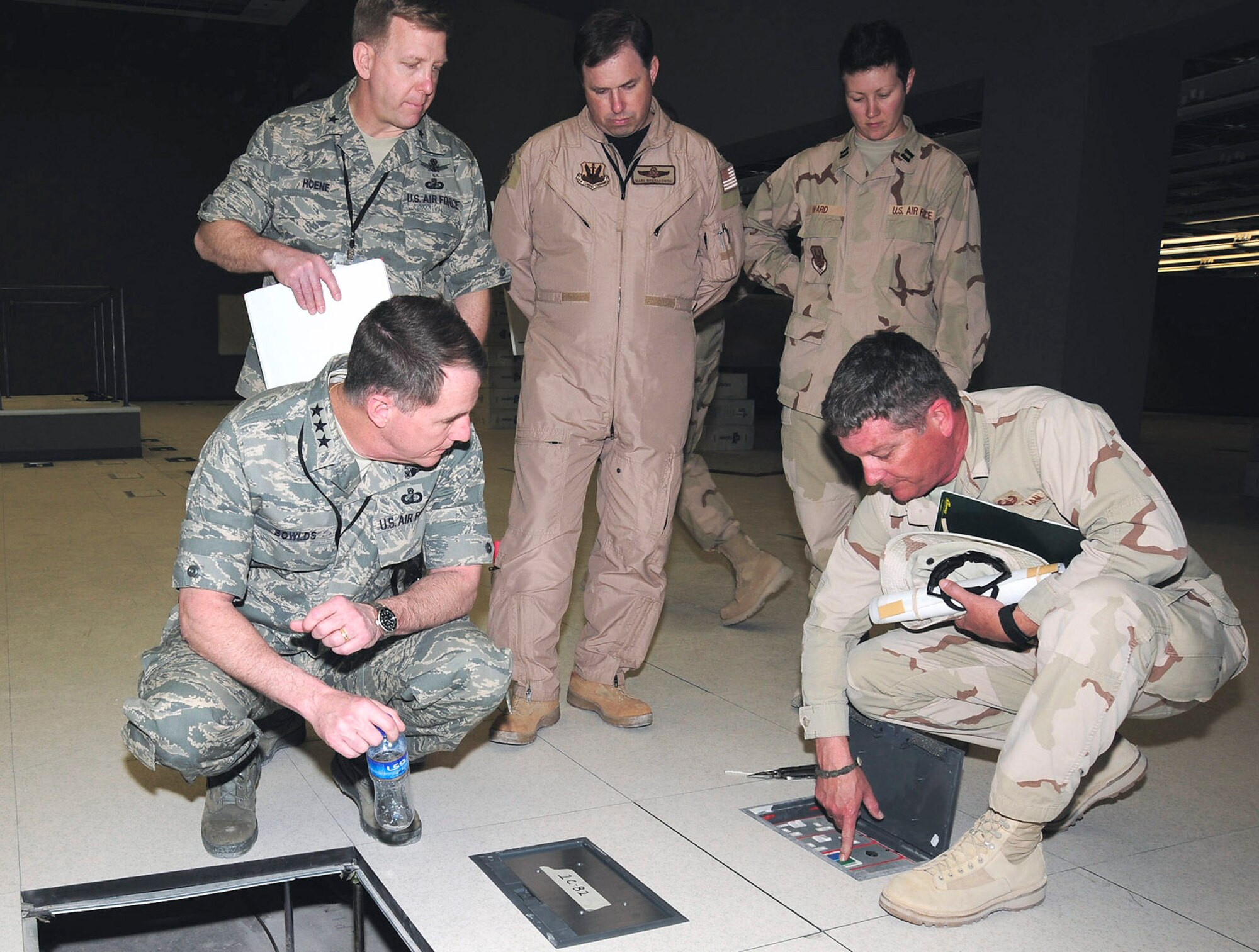 Lt. Gen. Ted F. Bowlds (clockwise from left), Brig. Gen. Peter F. Hoene, Col. Mark Bronakowski, Capt. Amber Ward and Hal Steinman examine the floor boxes in the Combined Air and Space Operations Center's new facility during General Bowlds' March 4 visit to the forward Southwest Asia location. The floor boxes will be the main source of power for the CAOC's workstations and phone lines once the summer installation takes place in July. General Bowlds is the Electronic Systems Center commander, and General Hoene is the 350th Electronic Systems Wing commander, both at Hanscom Air Force Base, Mass.  Colonel Bronakowski, Captain Ward and Mr. Steinman are members of the CAOC Program Management Office. (U.S. Air Force photo/Staff Sgt. Joshua Peargin) 
