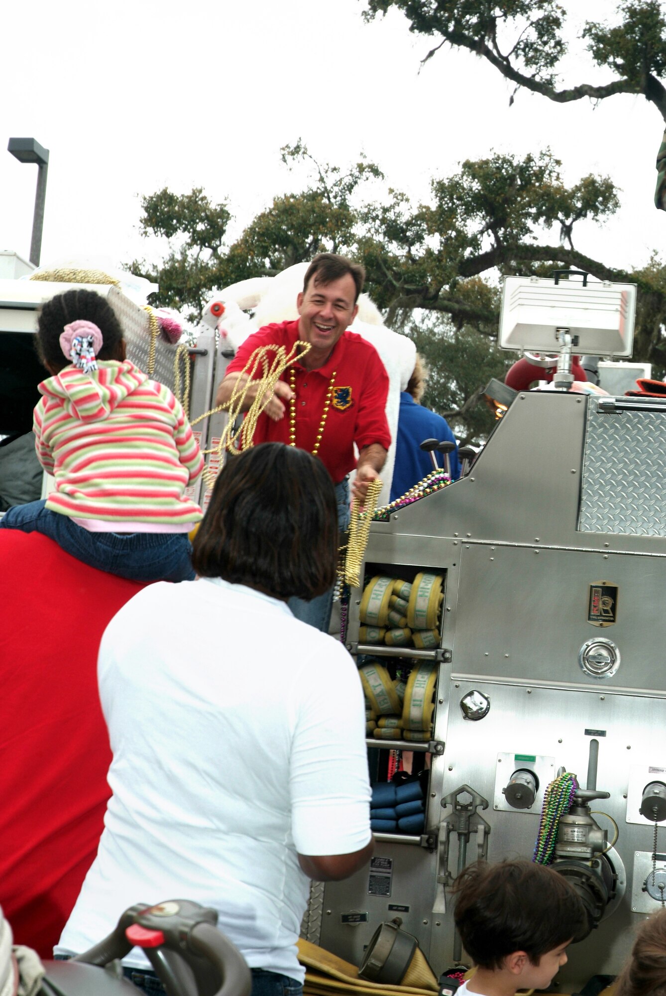 Col. Greg Touhill, 81st Training Wing commander, tosses beads to families attending Saturday’s Easter parade.  The Touhill family, riding on one of the base’s fire trucks, served as the parade’s grand marshals.  (U.S. Air Force photo by Adam Bond)