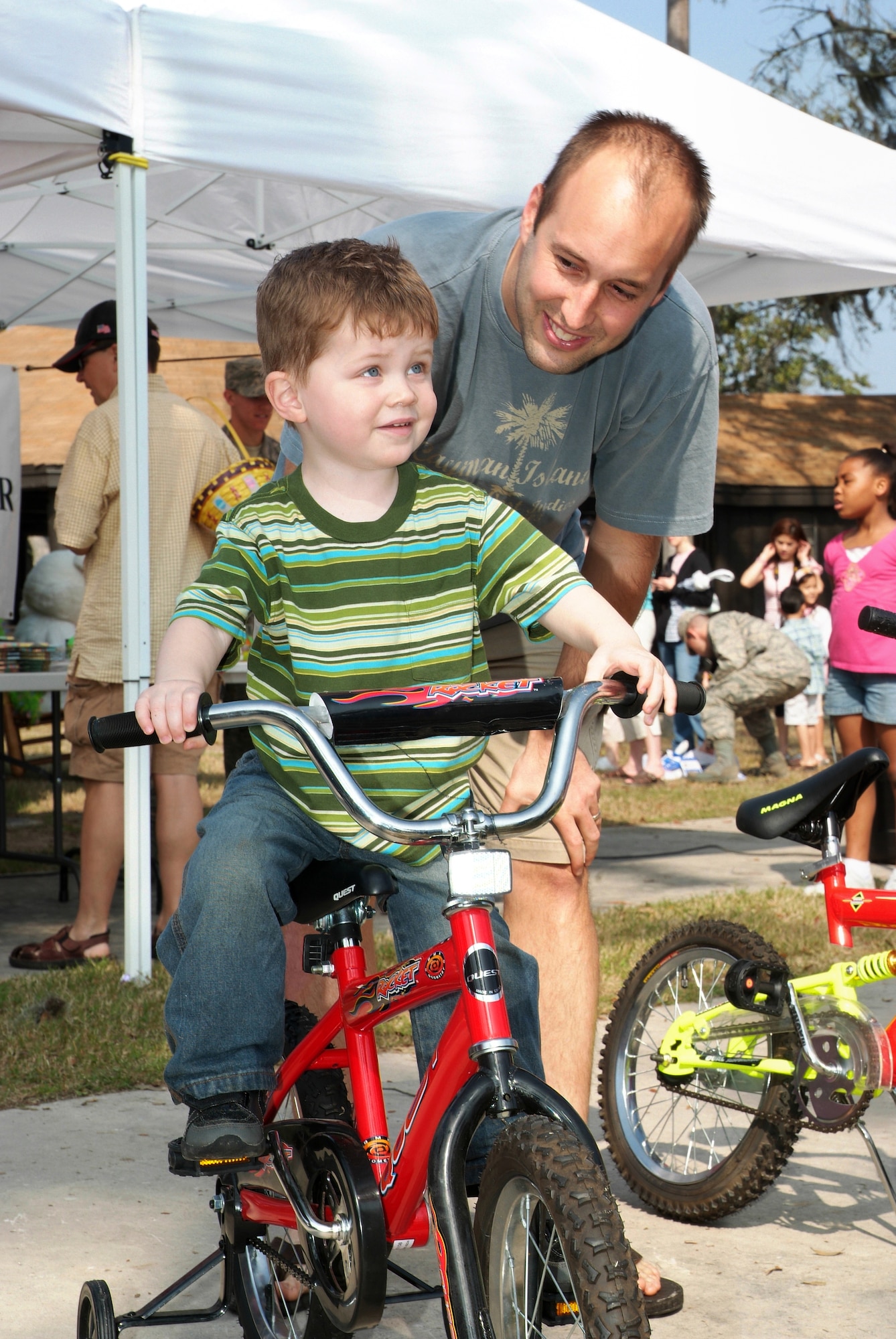 Will Gryzen, 3, gets some help from 1st Lt. Mark Williams with the bicycle he won at Keesler’s Easter celebration Saturday at marina park.  Will’s parents are Maj. Pete and Heidi Gryzen, 2nd Air Force.  Lieutenant Williams is assigned to the 81st Supply-Transportation Squadron.  (U.S. Air Force photo by Adam Bond)