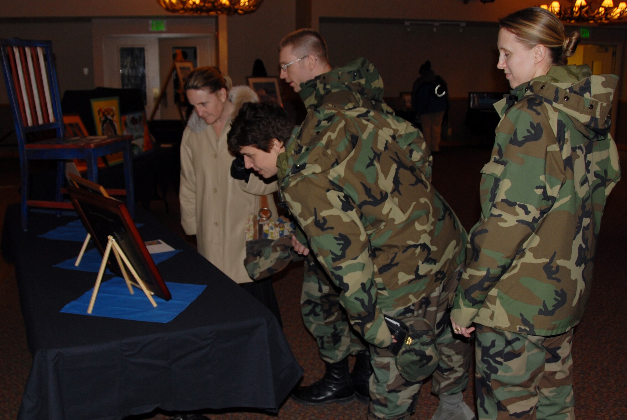 A group of military and civilians appreciate a particular piece of art March 21 during the women's history month art exhibit at the Yukon Club on Eielson Air Force Base, Alaska. With less than a month's planning by this year's committee, the event was made possible by a dozen military wives, daughters and civilians, who loaned nearly 30 art pieces to showcase this year's theme -- Women's Art, Women's Vision. (U.S. Air Force photo/Staff Sgt. Shad Eidson)