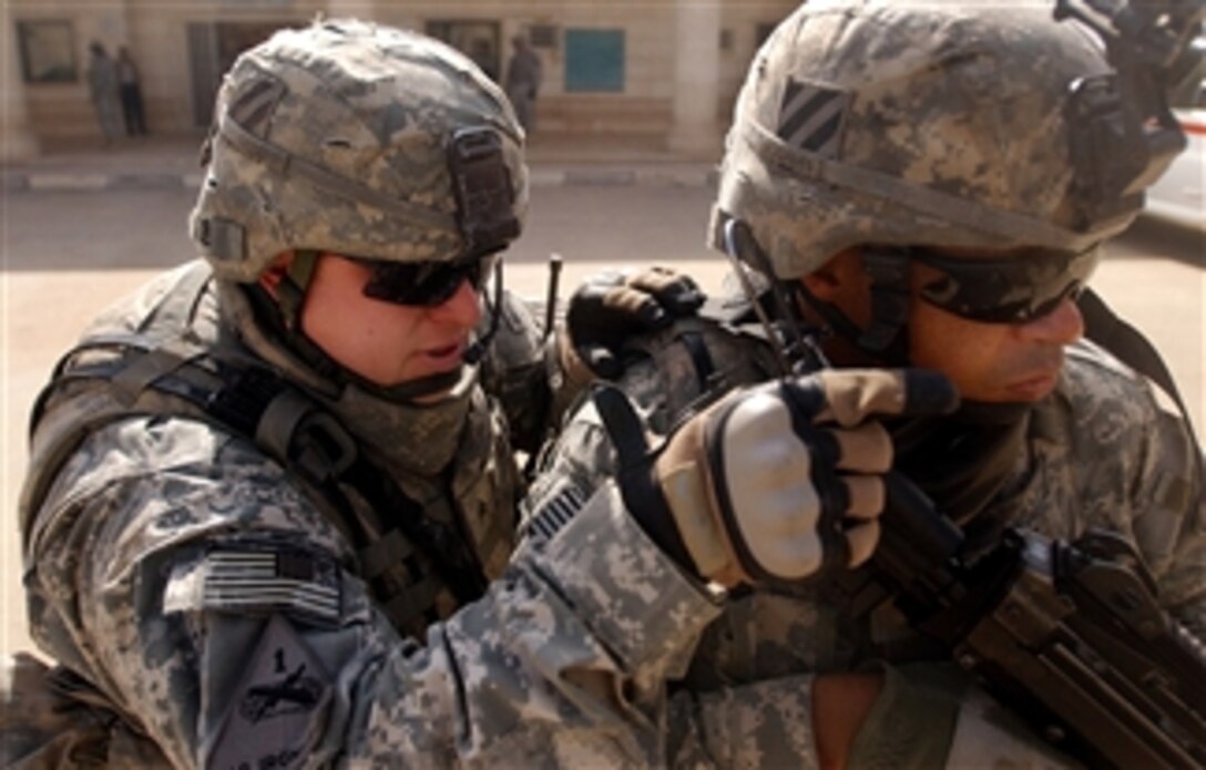 U.S. Army Sgt. Bobby Gilbert (left) points out a building to Spc. Jason Collins to watch for suspicious activity while providing security during a medical civic action program in Baghdad, Iraq, on Feb. 29, 2008.  Iraqi army doctors and medics are conducting the program to provide free medical care for Iraqi citizens.  