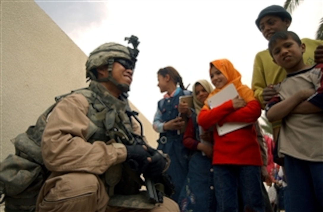 Sgt. Jonathan Huynh talks with Iraqi children while providing security outside the Noor al Mustafa School near Makasib, Iraq, on March 11, 2008.  Huynh is an infantryman with the 160th Long Range Surveillance Detachment and is providing security as soldiers from the 164th Engineer Battalion work with local contractors to rebuild and refurbish infrastructure items at the school.  