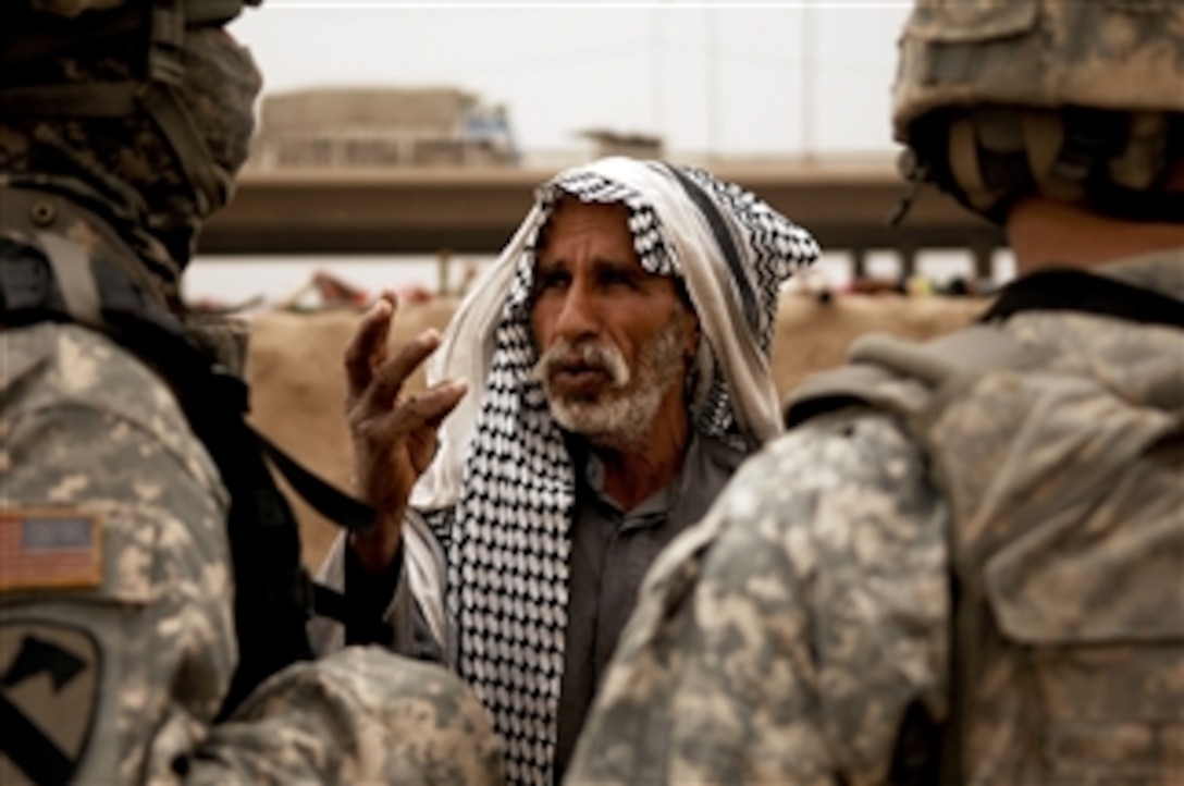 An Iraqi man talks to soldiers from the U.S. Army's Alpha Troop, 2nd Squadron, 14th Cavalry Regiment, 2nd Stryker Combat Brigade Team, 25th Infantry Division during a dismounted patrol through an area north of Baghdad, Iraq, on March 11, 2008.  