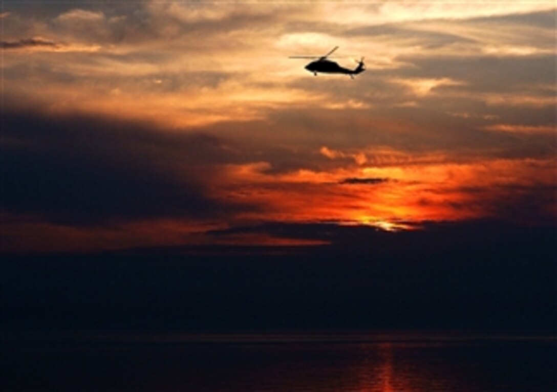 An MH-60S Knight Hawk helicopter assigned to Helicopter Sea Combat Squadron 21 flies past amphibious assault ship USS Tarawa  while under way in the Arabian Gulf, March 11, 2008. 