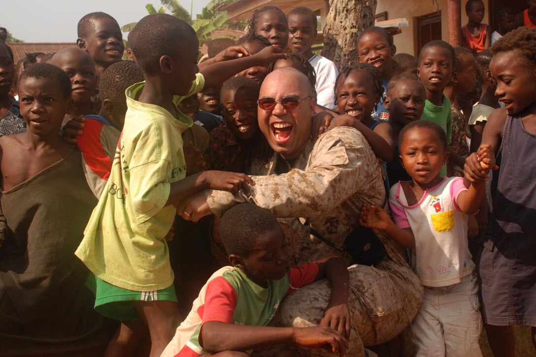Maj. Jason P. Smith, convoy commander and amphibious assault officer, takes time away from convoy operations to interact and play with some Liberian children during a convoy to deliver humanitarian supplies throughout the city of Monrovia, Liberia.