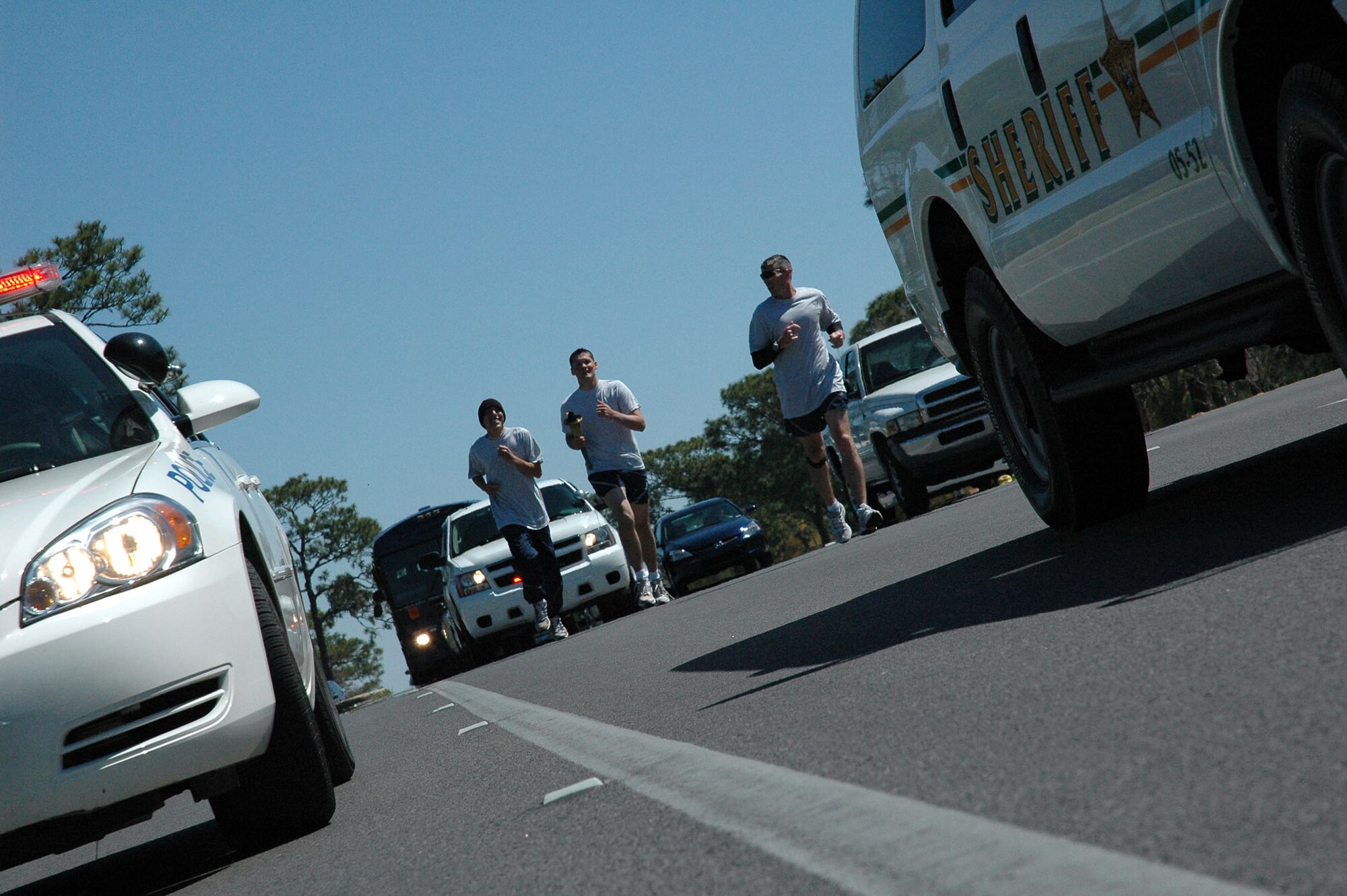 Staff Sgt. Scott Cousins, Airman 1st Class Kendal Herwald and Capt. Michael Small  continue the Torch Run across Eglin. The Florida Torch run is a grassroots program supported by local police departments as a fundraiser for the Special Olympics.  (U.S. Air Force Photo by Airman 1st Class Anthony Jennings)