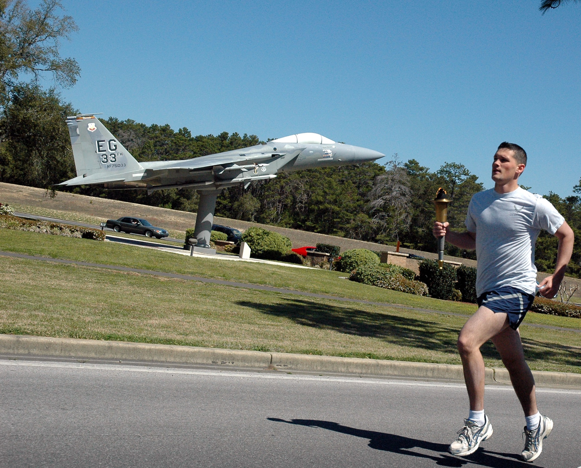 Airman 1st Class Kendal Herwaldcarries the torch as he passes the 33rd Fighter Wing's F-15 static display for The Florida Torch run, a grassroots program supported by local police departments as a fundraiser for the Special Olympics.  (U.S. Air Force Photo by Airman 1st Class Anthony Jennings)