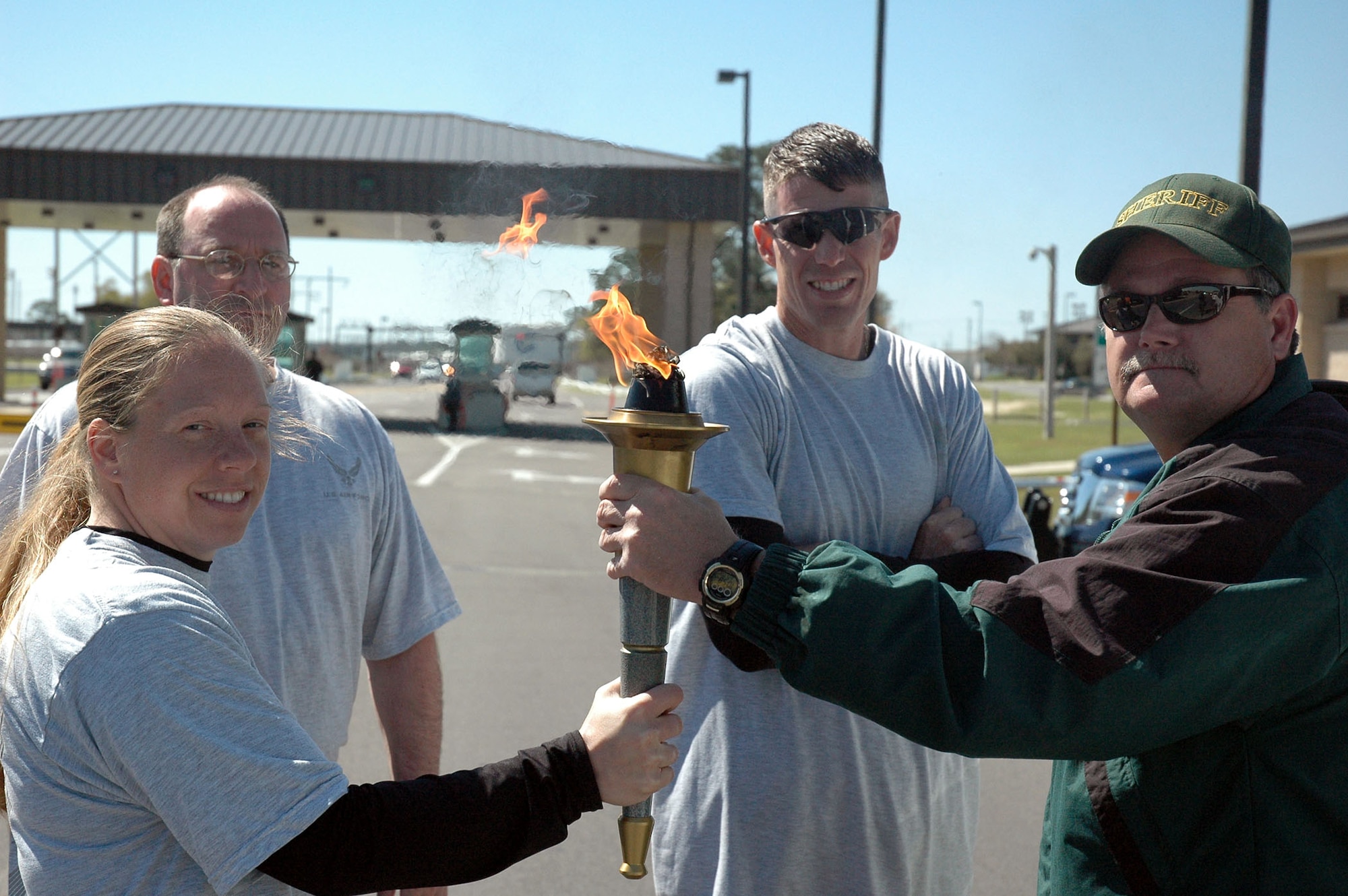 (From left) Tech. Sgt. Elizabeth Staub, Chief Master Sgt. Greg Morgan, Capt. Michael Small receive the torch from Okaloosa County Sheriff Lt. Wasdon to begin the Torch Run across Eglin. The Florida Torch run is a grass roots program supported by local police departments as a fundraiser for the Special Olympics.  (U.S. Air Force Photo by Airman 1st Class Anthony Jennings)