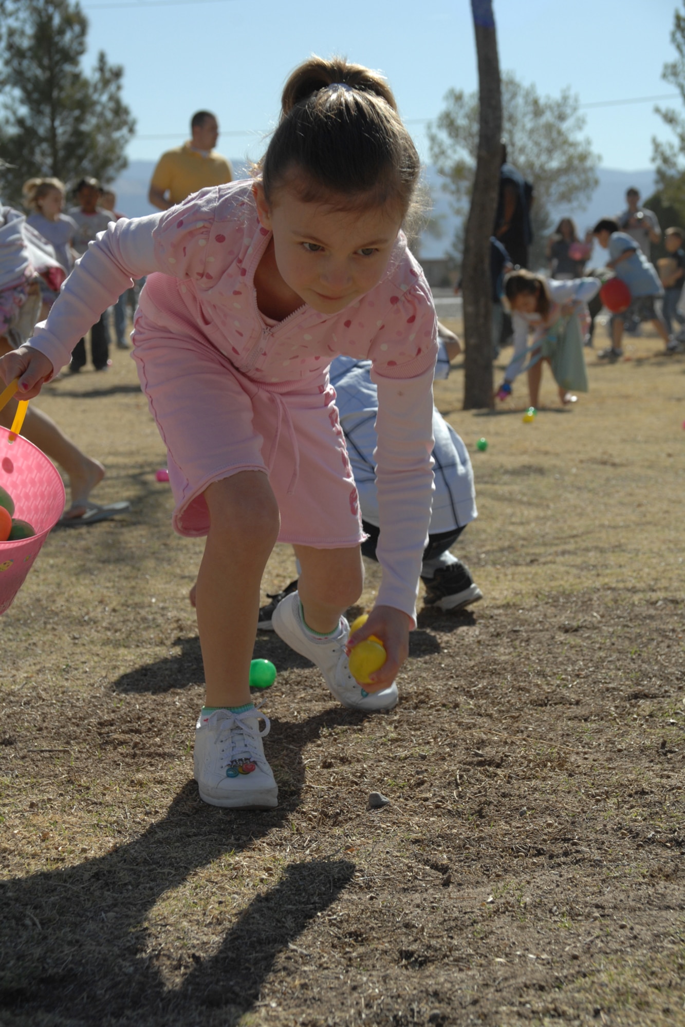 A girl collects eggs during the Base Wide Easter Egg Hunt March 22 at Steinhoff Park, Holloman Air Force Base, N.M. Six golden eggs were hidden throughout the park, which offered children chances to win prizes. (U.S. Air Force photo/Airman 1st Class Jamal D. Sutter)