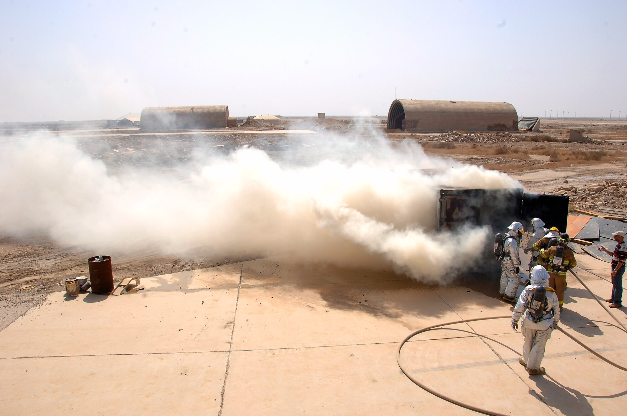 Air Force firefighters from the 407th Expeditionary Civil Engineer Squadron finish up one round of a "live burn," an exercise that gives the Iraqi firefighters, in yellow, a chance to attack real fire in a controlled environment March 3 at Ali Base, Iraq. The training allows the Iraqi firefighters to understand safety principles and the capabilities of the donated fire suits they are wearing. (U.S. Air Force photo/Staff Sgt. Nathan Gallahan) 
