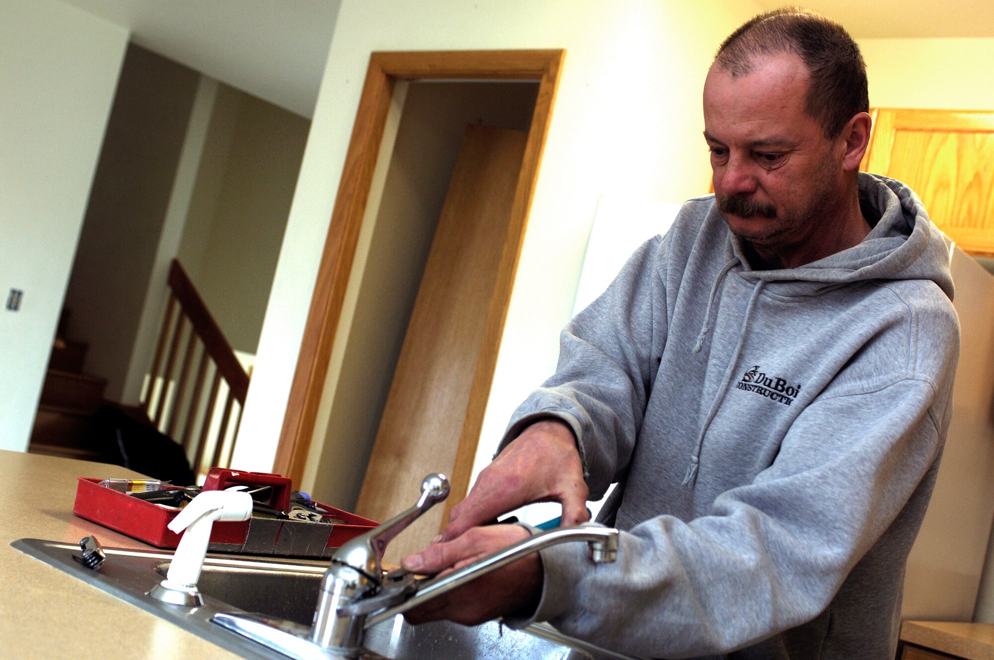 MINOT AIR FORCE BASE, N.D. -- Allan Berdahl, a housing maintenance repair technician with CS DuBois, repairs a kitchen faucet in a house here March 28. The house is undergoing a maintenance phase called "rehab," which consists of plumbing inspections and fixing major damages, before another tenant moves in. (U.S. Air Force photo by Airman 1st Class Kelly Timney)