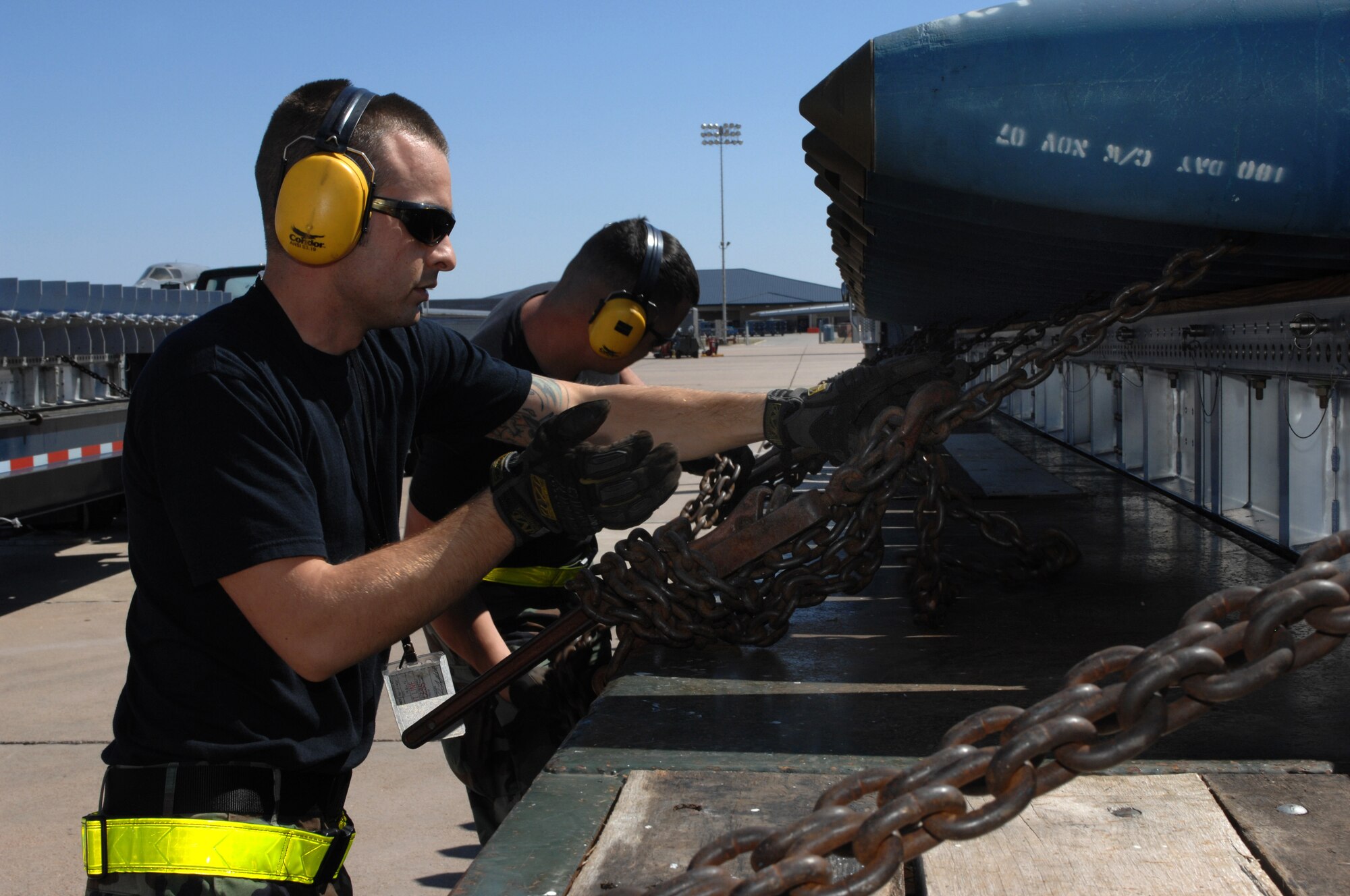 DYESS AIR FORCE BASE, Texas -- Senior Airman Mark Strona, 7th Munitions Squadron, secures a chain holding down bombs, March 19. Due to the size and weight of the bombs they have to be transported by flat bed trailer trucks. (U.S. Air Force photo by Senior Airman Courtney Richardson) 