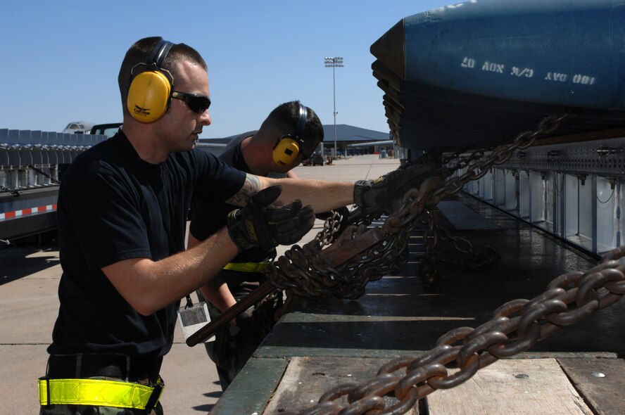 DYESS AIR FORCE BASE, Texas -- Senior Airman Mark Strona, 7th Munitions Squadron, secures a chain holding down bombs, March 19. Due to the size and weight of the bombs they have to be transported by flat bed trailer trucks. (U.S. Air Force photo by Senior Airman Courtney Richardson) 