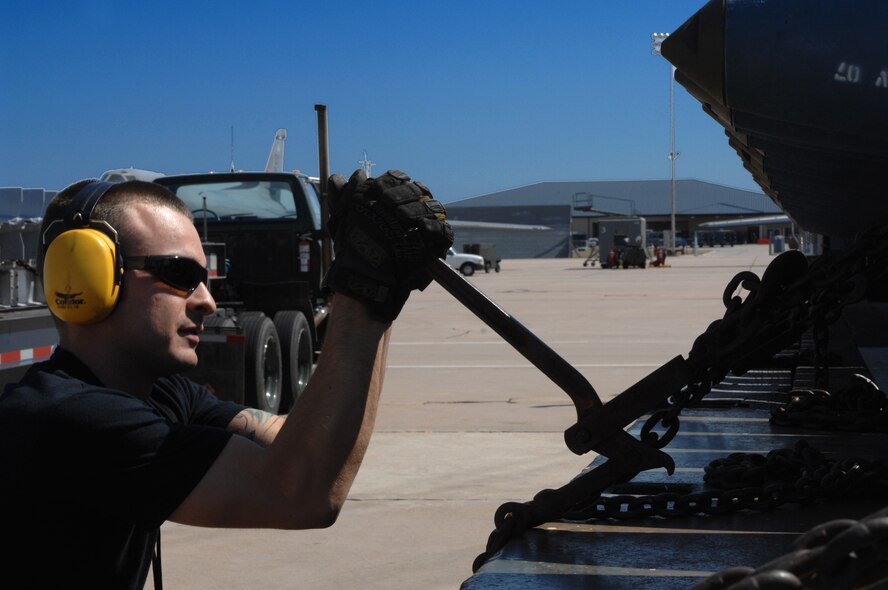 DYESS AIR FORCE BASE, Texas -- Senior Airman Mark Strona, 7th Munitions Squadron, tightens bombs for transport, March 19.  A B-1 Lancer has a 75,000 pounds payload. (U.S. Air Force photo by Senior Airman Courtney Richardson)