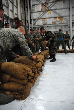 Airmen build a barrier wall during the Mobility Exercise Crisis Look 08-03 March 20 on the flightline. After training and if needed at a deployed location, Airmen would be required to build a wall that would be a minimum of four feet from the building that needs to be protected.  (U.S. Air Force photo/Staff Sgt. Jennifer Arredondo)