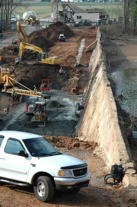 Workers for EMR Inc. are excavating the area behind the base's Big Lake dam and beginning to pour the concrete for reinforcement. The dam was built in 1906, and over time water has undermined the structure. The $3.7 million project will provide additional reinforcement and allow the lake to continue protecting the area from potential flooding on and off base.  (U.S. Air Force photo/Micah Garbarino)
