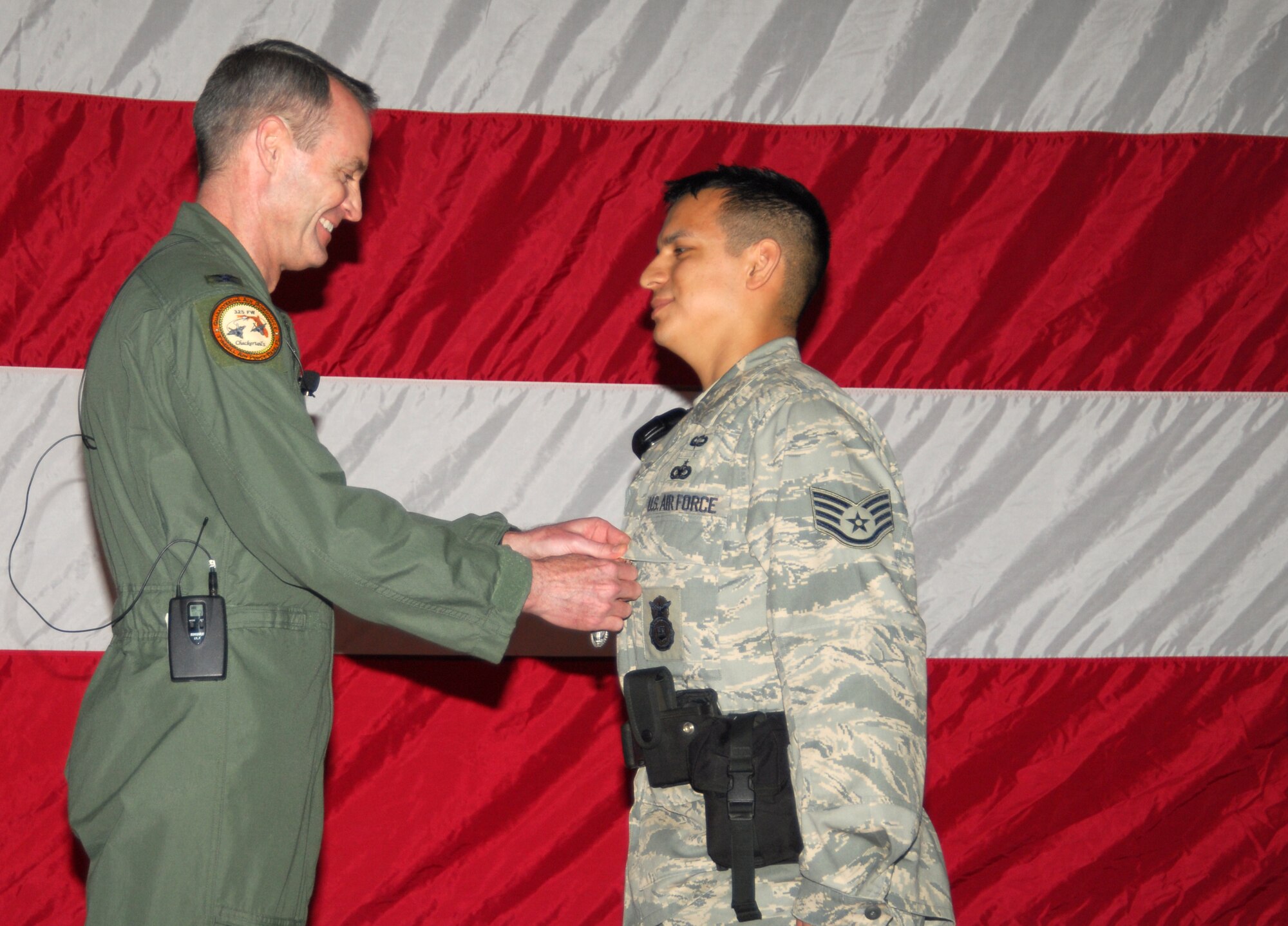 Col. Darryl Roberson, 325th Fighter Wing commander, pins the Air Force Combat Action Medal to Staff Sgt. Cesar Flores, 325th Security Forces Squadron flight chief, during the Commander’s Call ceremony here March 14.  (U.S. Air Force photo/Lisa Norman)