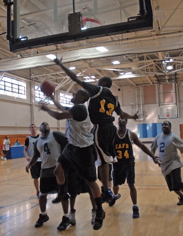 Travonte Gooden, APS, fights off SVS defenders on his way to the hoop during the intramural basketball game Tuesday. (U.S. Air Force photo/Senior Airman Sam Hymas)