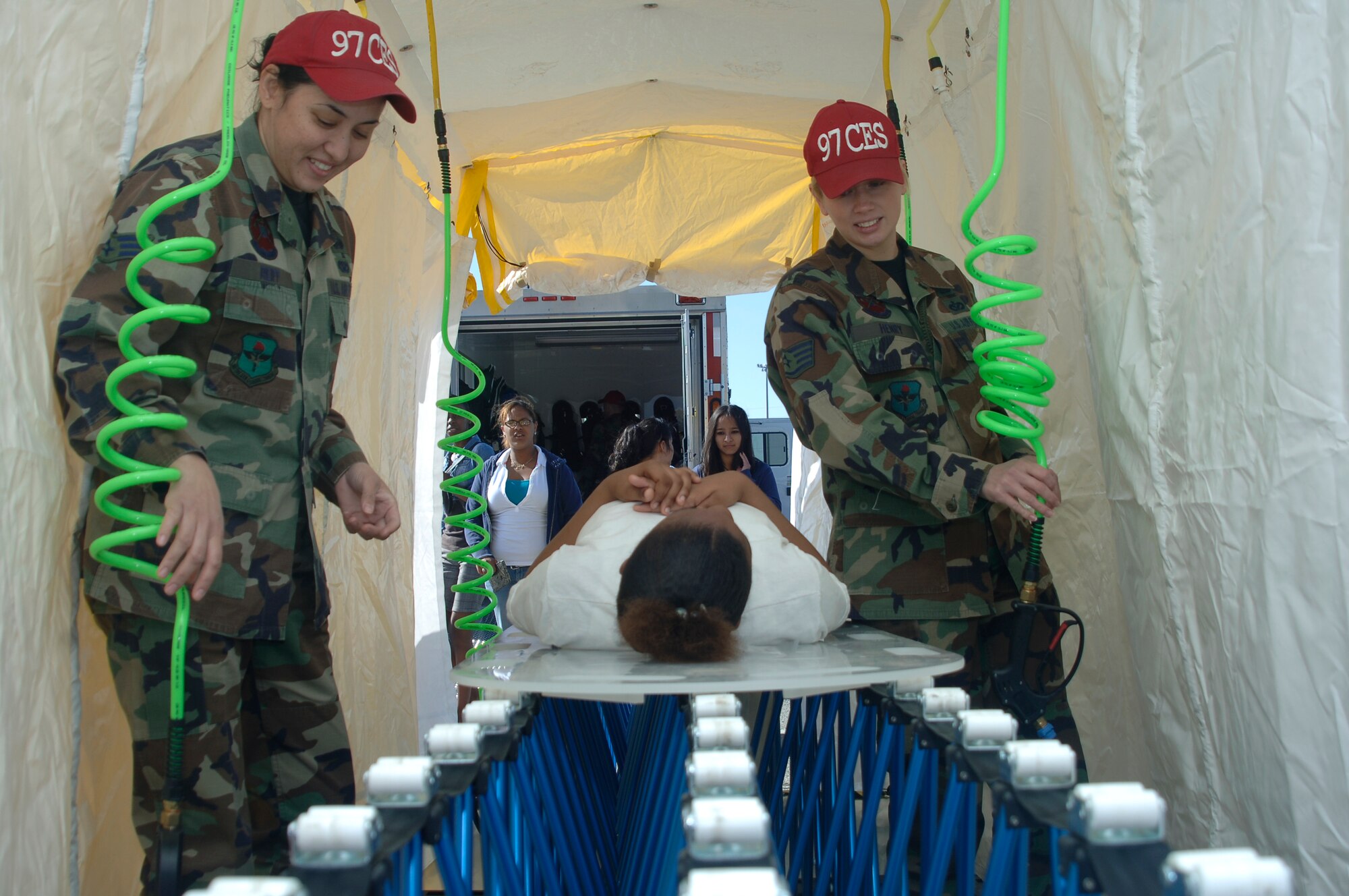 ALTUS AIR FORCE BASE, Okla. -- Left, Senior Airman Maria Reiff and, right, Staff Sgt. Renaissance Henry, 97th Civil Engineering Squadron, demonstrate the operation of the decontamination tent during Career Day March 25. Mountain View-Gotebo, Blair and Altus High Schools participated. The High School students were also briefed by South West Technology Center and an Air Force recruiter. (U.S. Air Force photo/Airman 1st Class Amanda Bower)
