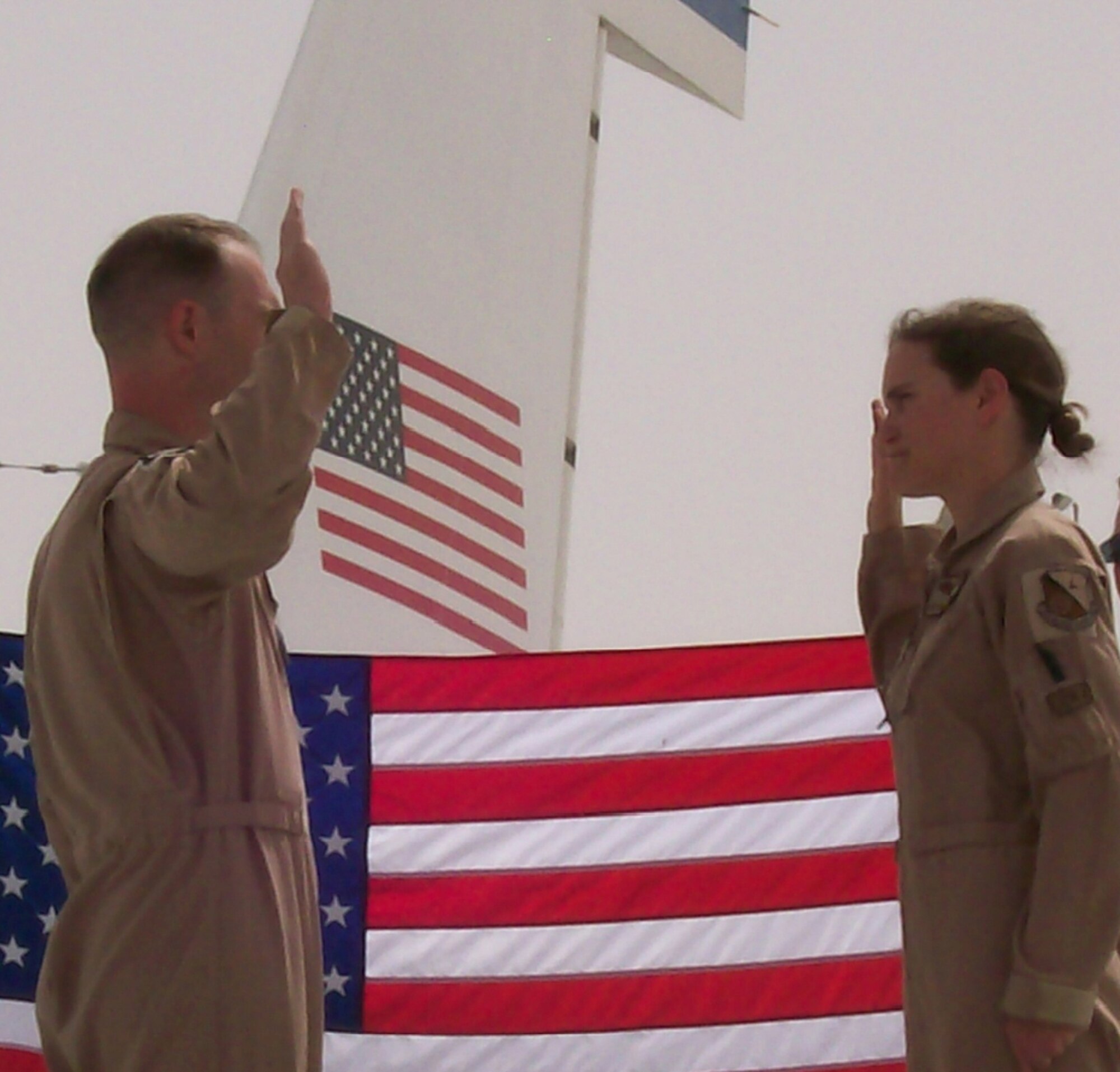 Captain Zachary Stevens, 763rd Expeditionary Reconnaissance Squadron, administers the oath of reenlistment to Senior Airman Kristen Van Slyke, 763rd ERS, on the wing of an RC-135 Rivet Joint aircraft. Airman Van Slyke, along with many other women deployed to the 379th Air Expeditionary Wing, continue the proud heritage of past women aviators and Airmen by their continued dedication and service. Both Captain Stevens and Airman Van Slyke are deployed from Offutt. (Courtesy Photo)