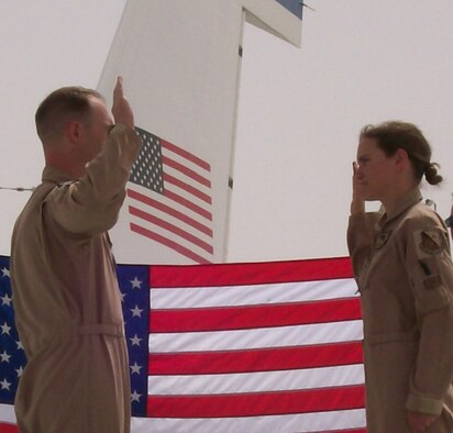 Captain Zachary Stevens, 763rd Expeditionary Reconnaissance Squadron, administers the oath of reenlistment to Senior Airman Kristen Van Slyke, 763rd ERS, on the wing of an RC-135 Rivet Joint aircraft. Airman Van Slyke, along with many other women deployed to the 379th Air Expeditionary Wing, continue the proud heritage of past women aviators and Airmen by their continued dedication and service. Both Captain Stevens and Airman Van Slyke are deployed from Offutt. (Courtesy Photo)