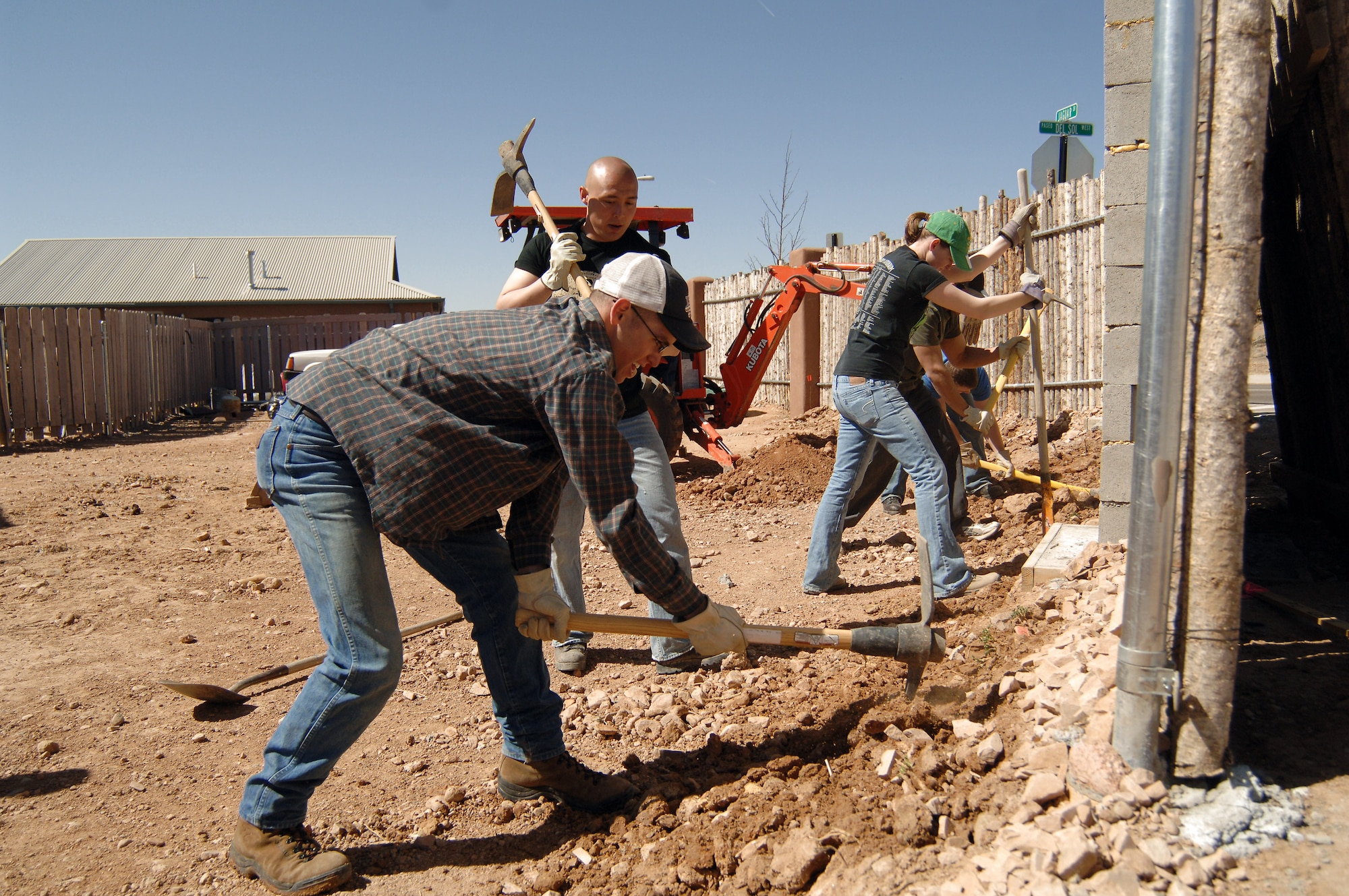 Cadet 3rd Class Ben Shoptaugh (front) and Cadet 4th Class Anthony Langdon take their turns with pick-axes as Cadet 2nd Class Dani Rogowski uses a shovel to clear away the broken rocks and dirt and fellow cadets make short work of a land-clearing project in Santa Fe. Cadets Rogowski, Shoptaugh and Langdon are part of the 65 Air Force Academy cadets who are giving up their spring break this week to build homes for the needy in Santa Fe, N.M.; Cody, Wyoming; El Paso, Texas; and Beaumont, Texas. (U.S. Air Force photo/John Van Winkle) 
