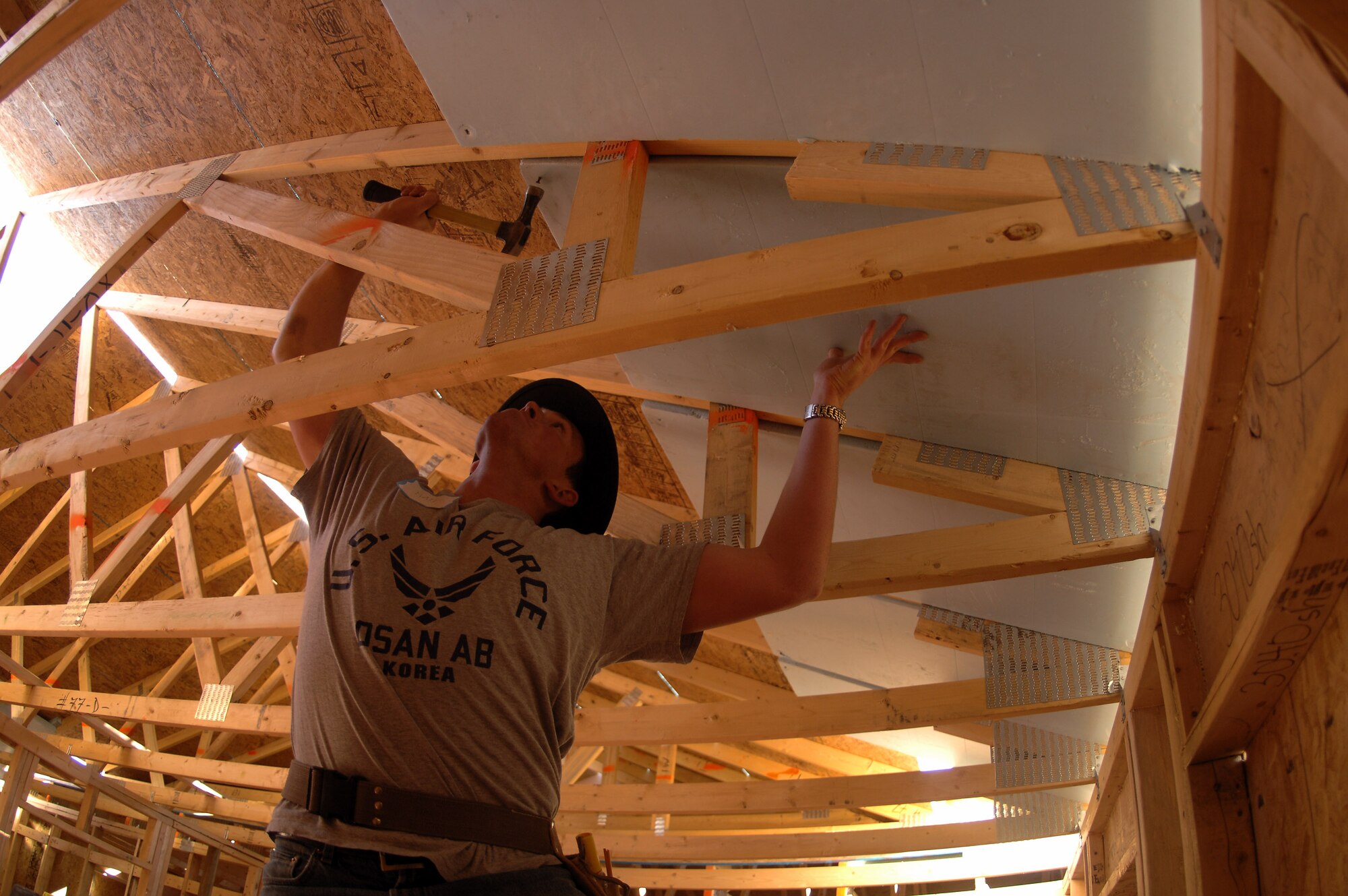 Cadet 3rd Class Matt Guertin holds insulation steady while nailing it in place. Cadet Guertin is one of 65 Air Force Academy cadets giving up their spring break this week, to build homes for the needy in Santa Fe, N.M.; Cody, Wyoming; El Paso, Texas; and Beaumont, Texas. (U.S. Air Force photo/John Van Winkle) 