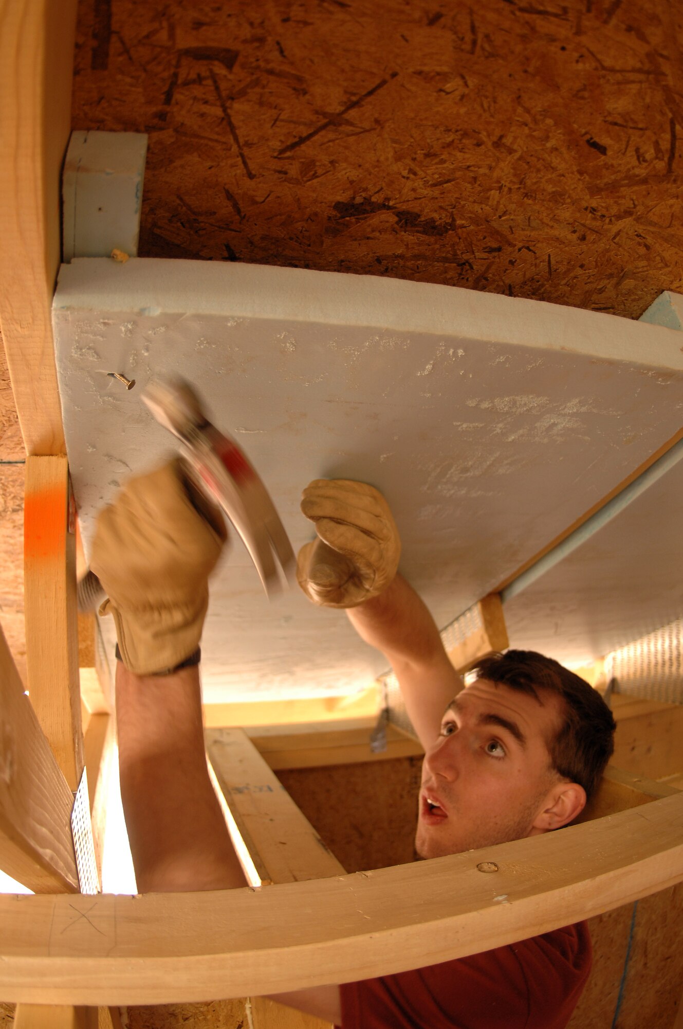 Cadet 3rd Class John Ball maneuvers in a tight spot to secure a piece of insulation in place. Cadet Ball is one of 65 Air Force Academy cadets giving up their spring break this week, to build homes for the needy in Santa Fe, N.M.; Cody, Wyoming; El Paso, Texas; and Beaumont, Texas. (U.S. Air Force photo/John Van Winkle)  