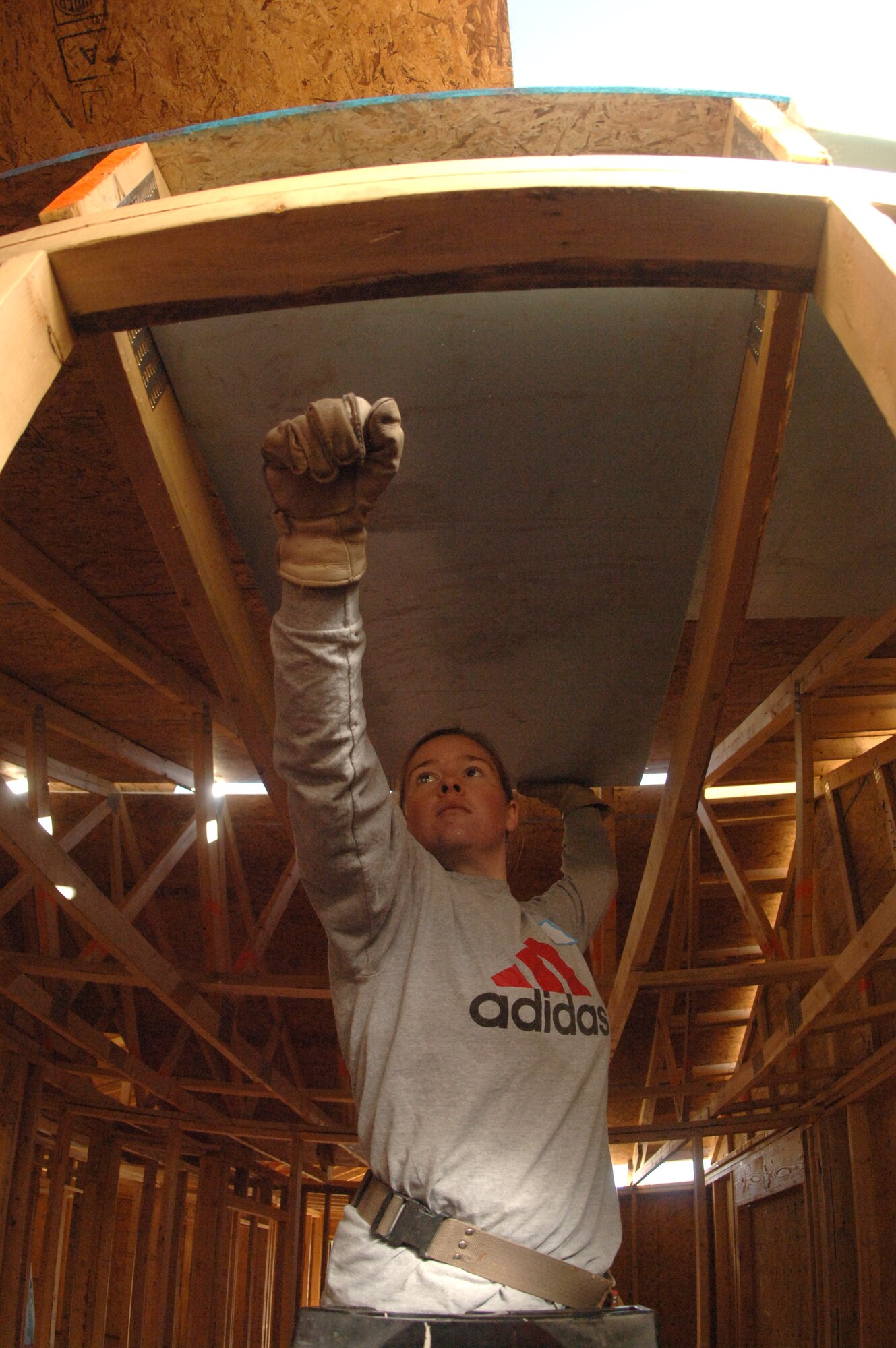 Cadet 4th Class Michelle Paranteau persuades a tight-fitting piece of insulation in place with her fist, while helping build a home during her spring break, via Habitat for Humanity. Cadet Paranteau is one of 65 Air Force Academy cadets giving up their spring break this week, to build homes for the needy in Santa Fe, N.M.; Cody, Wyoming; El Paso, Texas; and Beaumont, Texas. (U.S. Air Force photo/John Van Winkle) 