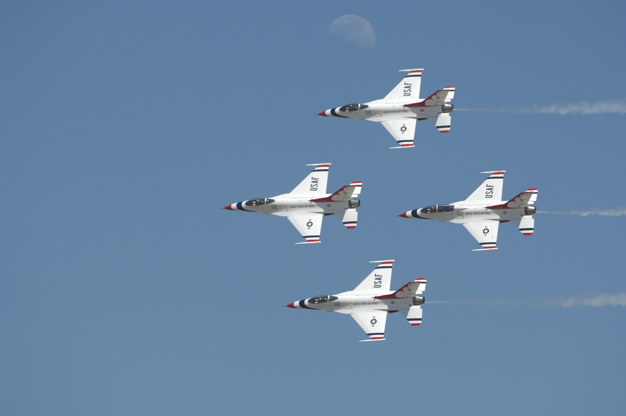 The United States Air Force Thunderbirds fly by in a diamond pass in review during Air Fiesta ’08 March 15, as the moon rises behind them over San Angelo Regional Airport Mathis Field in San Angelo, Texas. Piloting the four-ship formation of F-16 Fighting Falcons are Lt. Col. Greg Thomas (Thunderbird 1, lead), Maj. Chris Austin (Thunderbird 2, left wing), Maj. Kirby Ensser (Thunderbird 3, right wing) and Maj. Scott Poteet (Thunderbird 4, slot). Two additional pilots, Maj. Samantha Weeks and Maj. T. Dyon Douglas, fly lead and opposing solo, respectively, and six additional officers and 113 enlisted Airmen round out the team. The Thunderbirds, headquartered at Nellis Air Force Base, Nev., are the Air Force’s premier aerial demonstration team, and Air Fiesta ‘08 marks their first air show in the 2008 season. (U.S. Air Force photo by Staff Sgt. John Barton)