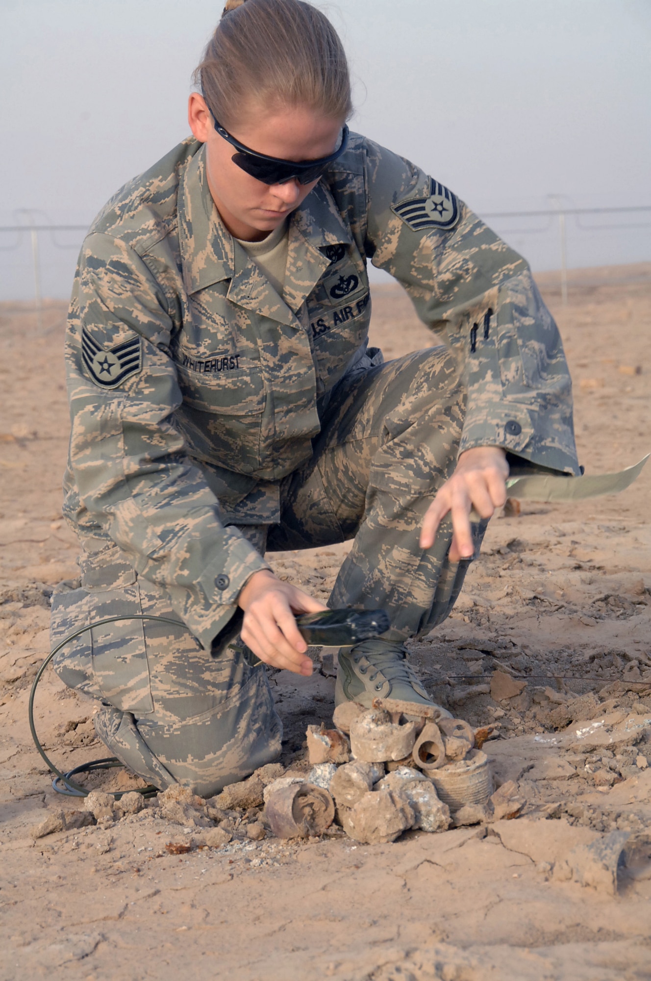 ALI Base, Iraq -- Staff Sgt. Molly Whitehurst, 407th Expeditionary Civil Engineer Squadron EOD team chief, places C4 on hazardous ordnance items to be detonated.  A six-Airman Explosive Ordnance Disposal team with an additional six augmentees walked through 159 acres of unexploded ordnance fields picking up debris and marking un-removable items for detonation March 26.  Sergeant Whitehurst is deployed from Kadena AB, Japan.  (U. S. Air Force photo / Tech. Sgt. Sabrina Johnson)