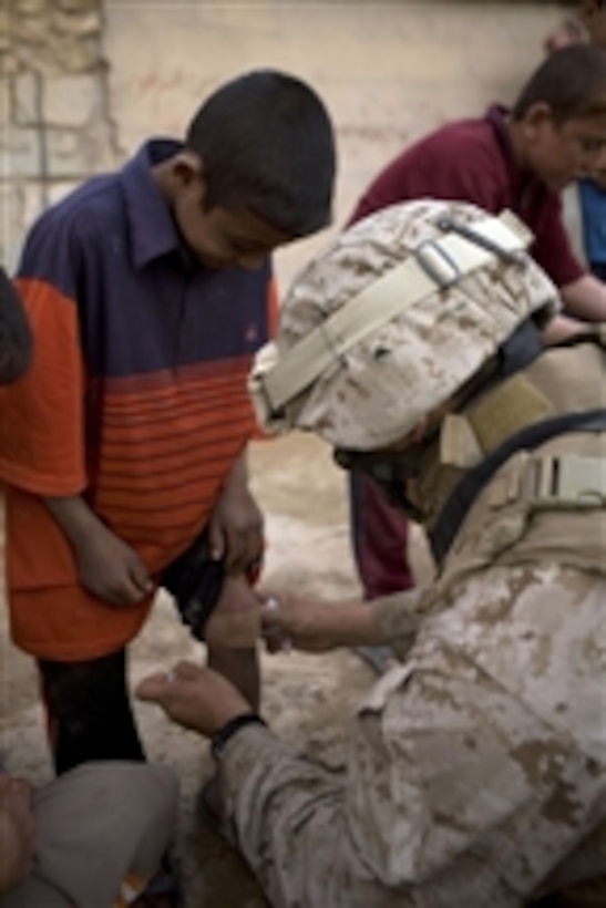U.S. Navy Hospitalman Mate 3rd Class Reymundo R. Parra from 1st Platoon, India Company, 3rd Battalion, 4th Marine Regiment, Regimental Combat Team 5 provides medical aid to a young Iraqi boy during a security patrol in Hit, Iraq, on March 14, 2008.  