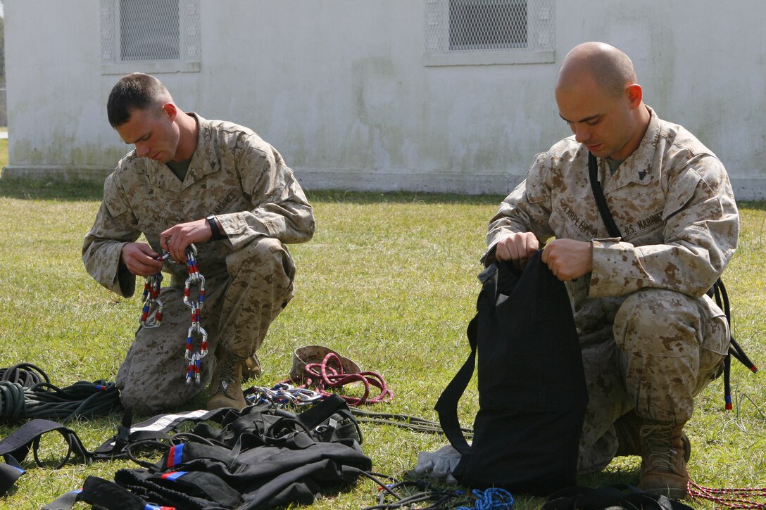 Lance Cpl. Christopher Austin (left), a rifleman with Company E, 2nd Battalion, 6th Marine Regiment, 2nd Marine Division, II Marine Expeditionary Force, and Cpl. Jeffrey Tarpley (right), a scout with 2nd Light Armored Reconnaissance Battalion, 2nd Marine Division, II MEF, check their gear here March 26 before rappelling down a 120 foot tower. Rappelling is one of many techniques taught in the Assault Climbers Course.