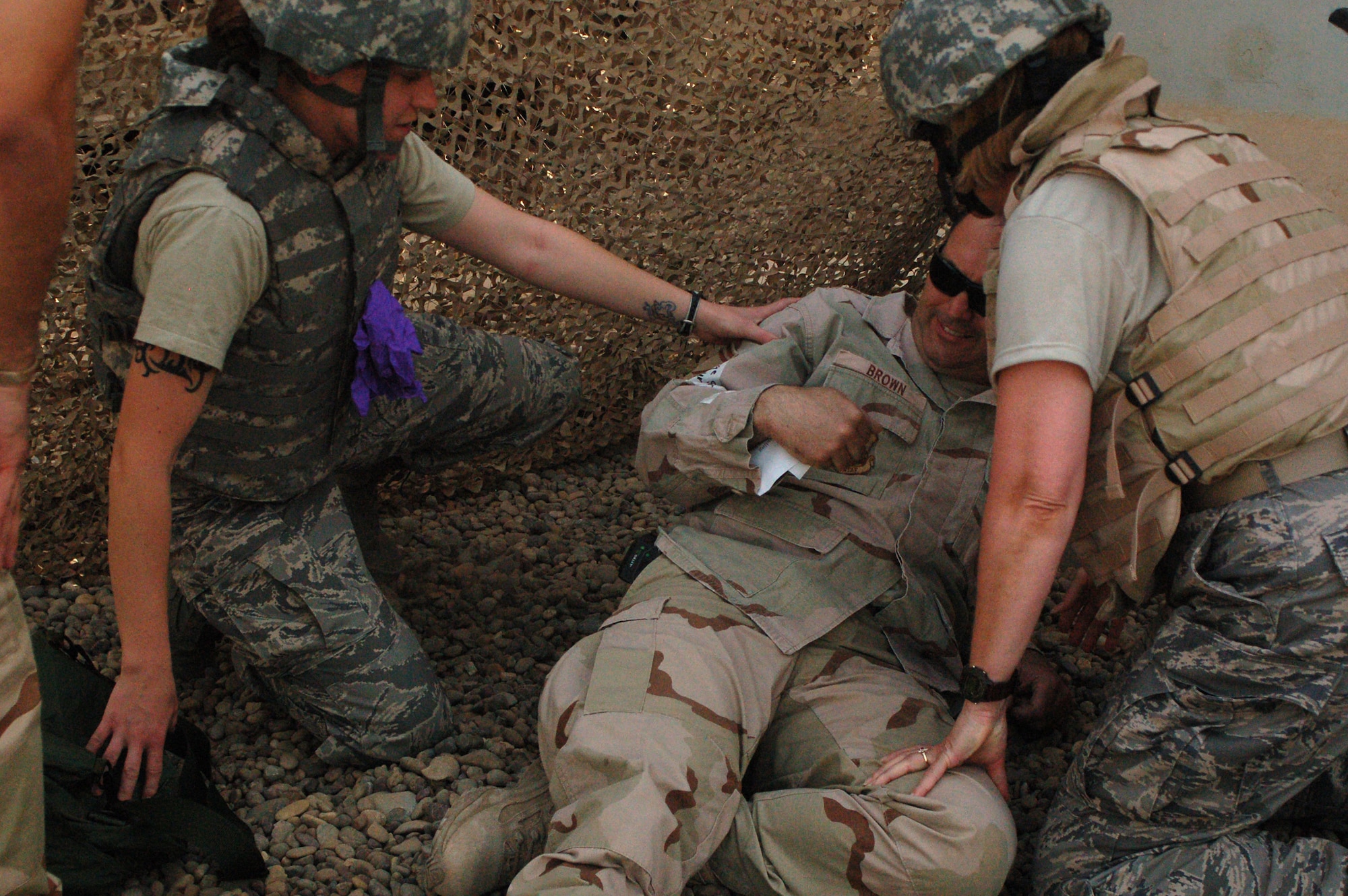 Staff Sgt. Jalayne Powers (left) and Lt. Col. Patricia Hartman assess the simulated injuries of Senior Master Sgt. Michael Brown March 21 at Sather Air Base, Iraq. The injuries are the result of a simulated unexploded oridence detination. The training teaches medical skills to non-clinical unit members. Sergeant Powers is a 447th Expeditionary Medical Squadron bioenvironmental engineer technician. Colonel Hartman is the chief administrator with the 447 EMEDS. Sergeant Brown is the 447th Expeditionary Civil Engineer Squadron's fire department fire chief. (U.S. Air Force photo/Tech. Sgt. Amanda Callahan) 