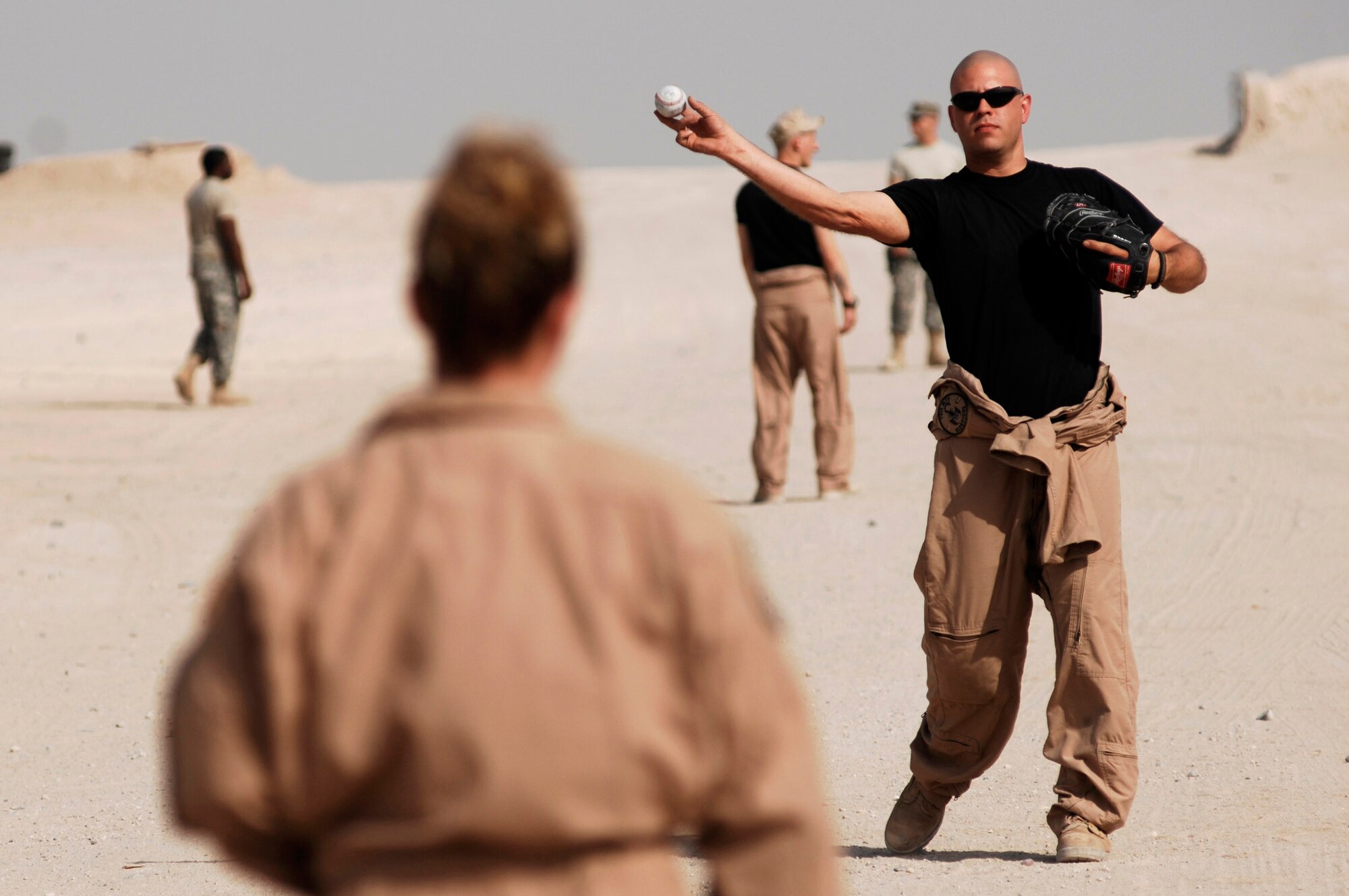 Senior Airman Jacob Workman plays catch with Staff Sgt. Tiffany Jennings during some free time before starting the next leg of their convoy from an Army camp in Southwest Asia. Both Airmen are vehicle operators from the 586th Expeditionary Logistics Readiness Squadron, 70th Medium Truck Detachment. The Airmen of the 70th and 424th MTDs assigned to the 586th ELRS are in-lieu-of forces supporting the Army support line-haul convoy movements in and out of Iraq. Airman Workman is deployed from Moody Air Force Base, Ga., and Sergeant Jennings is deployed from Pope AFB, N.C. (U.S. Air Force photo/Staff Sgt. Patrick Dixon) 
