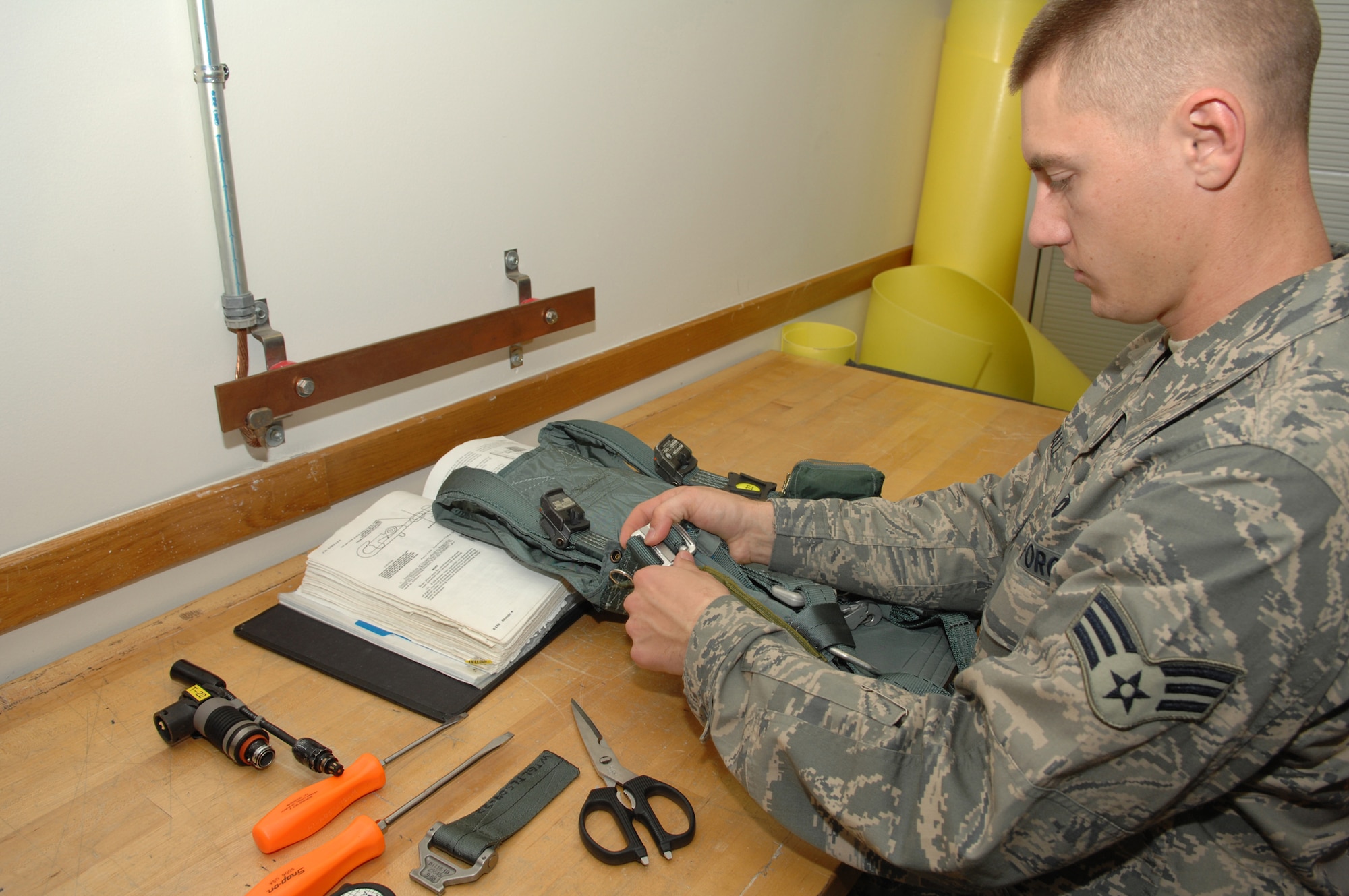 WHITEMAN AIR FORCE BASE, Mo. - Senior Airman Erick Hall, 393rd Bomb Squadron, Aircrew Flight Equipment specialist inspects a PCU-15a harness. Harnesses are inspected every 30 days for damage. Aircrew Flight Equipment Specialist’s are capable of making repairs to equipment as needed.  (U.S. Air Force Photo/ Senior Airman Jessica Snow)