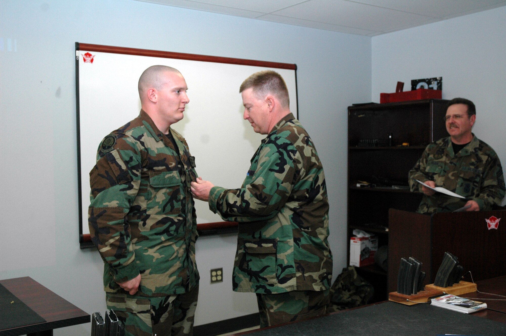 Lt. Col. Lynden Skinner, 341st Security Forces Group deputy commander, pins the Non-National Bronze Medal on Senior Airman Jeremy Thatcher, 341st Security Forces Group Tactical Response Force and winner of first place in the Excellent in Competition, pistol discipline, as Chief Master Sgt. Larry Wilson, 341st Security Forces Group superintendentlooks on. The EIC was held here March 17 to 22 and gave 180 members of Team Malmstrom a chance to compete for this medal. (U.S. Air Force photo/Airman 1st Class Emerald Ralston)