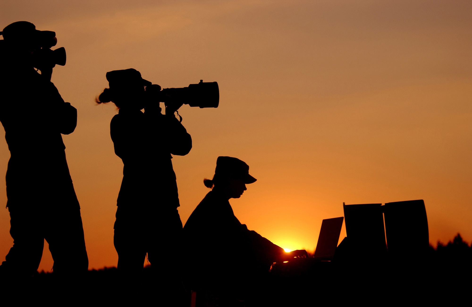An Air Force videographer (left to right), a still photographer and a graphics specialist are all highlighted by the setting sun. Airmen earned 13 first place awards, nine second place awards and 11 third place awards in the Defense Department 2007 Visual Information Awards contest. (U.S. Air Force photo)