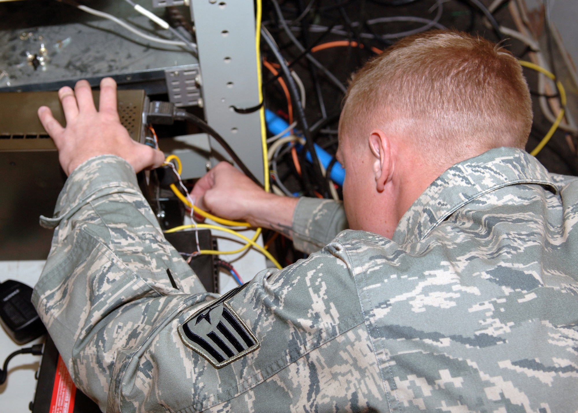 DYESS AIR FORCE BASE, Texas -- Staff Sergeant Nicholas Siburt reattaches wires coming from the back of a quantar station in the frame room located in the base command post, March 25. The station is responsible for transmitting digital signals to wireless radios in the fire station and on the flight line. (U.S. Air Force Photo by Airman 1st Class Micheal Breaux)