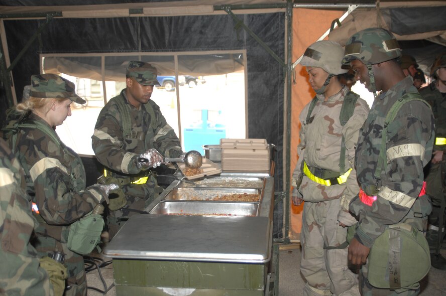 SEYMOUR JOHNSON AIR FORCE BASE N.C. - Airmen 1st Class Kristina Willison and Brian Delacruz, 4th Force Support Squadron, serve meals during the noon meal at the dining facility in Tent City during an operational readiness exercise March 18. The purpose of the exercise is to evaluate the 4th Fighter Wing's ability to survive and operate (ATSO), employ aircraft and resources, and conduct mission support activities in a steady state combat environment, and to provide training opportunities to improve on existing capabilities. (U.S. Air Force photo by Senior Airman Chad Trujillo) 