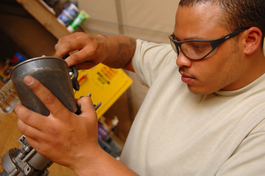 BALAD AIR BASE, Iraq -- Senior Airman Derand Javier, 64th Aircraft Maintenance Unit weapons specialist, safety wires a component that feeds and de-links the rounds as they move through a minigun of an HH-60G Pave Hawk helicopter here, March 26. A minigun is an aircraft machine gun consisting of a rotating cluster of six barrels using 7.62mm ammunition and capable of variable rates of fire. Airman Javier is deployed from Moody Air Force Base, Ga. (U.S. Air Force photo\ Senior Airman Julianne Showalter)