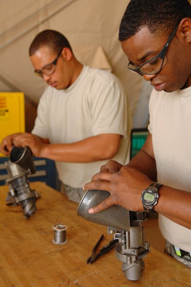 BALAD AIR BASE, Iraq -- Senior Airmen Derand Javier and Chris Moore, 64th Aircraft Maintenance Unit weapons specialists, safety wire components of a minigun here, March 24. A minigun is an aircraft machine gun consisting of a rotating cluster of six barrels using 7.62mm ammunition and is capable of variable rates of fire. The piece is used to feed and de-link the rounds as they move through the gun on an HH-60G Pave Hawk helicopter. Both Airmen are deployed from Moody Air Force Base, Ga. (U.S. Air Force photo\ Senior Airman Julianne Showalter)