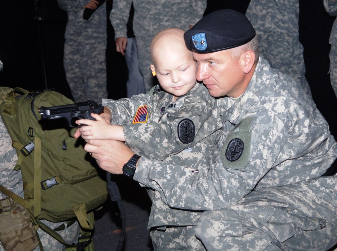 Army Maj. Gen. Russell Czerw, Fort Sam Houston, Texas, installation commander, teaches 5-year-old Gavin Cox how to shoot an M-9 pistol at the ES 2000 weapons training facility. Gavin also trained on an M-16 rifle and walked away with a marksmanship badge. Photo by Ed Dixon

