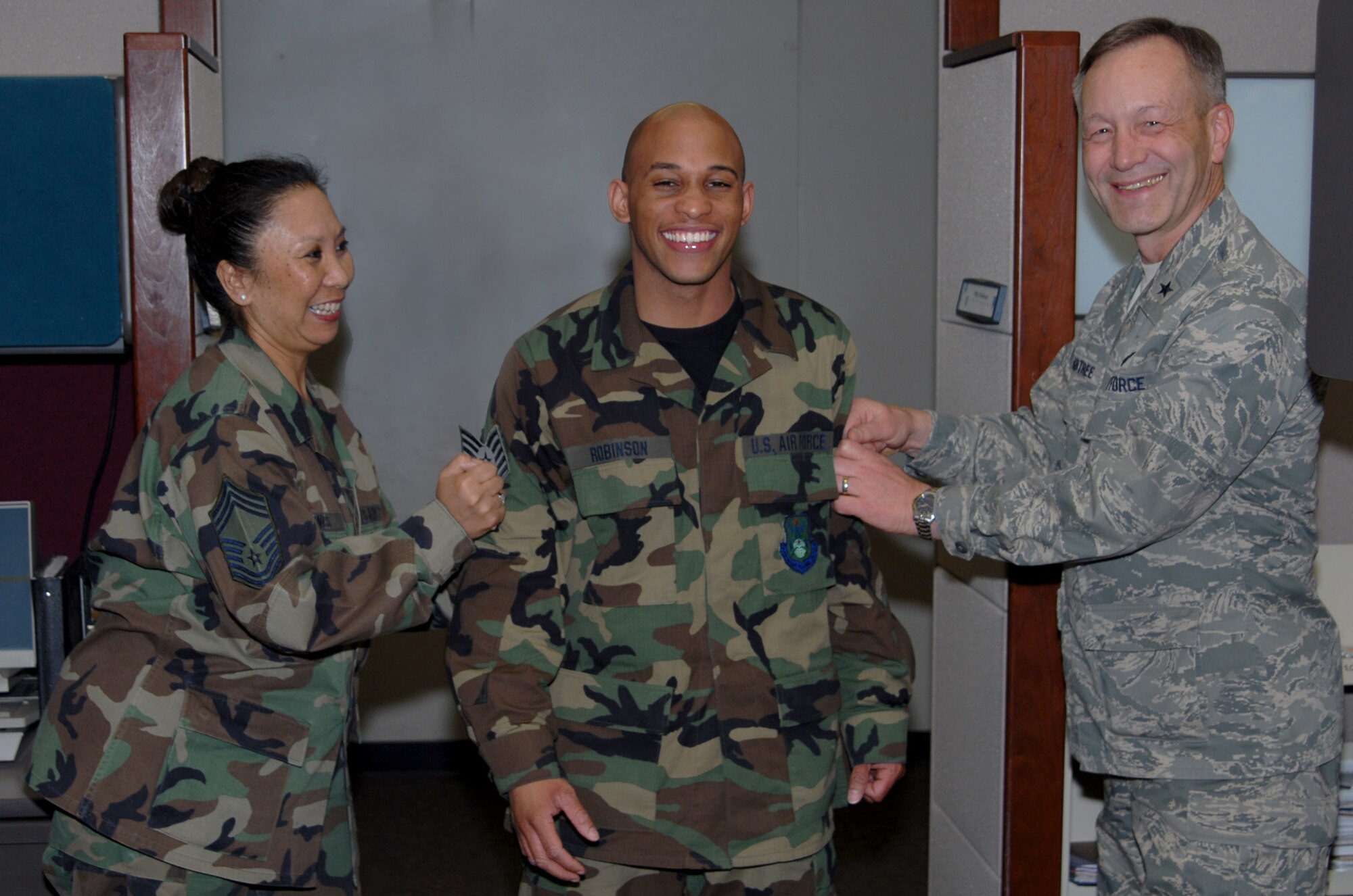 Staff Sgt. Michael Robinson, DPS, is tacked by Brig. Gen. Eric Crabtree, ARPC commander, and Chief Master Sgt. Fatima Jones, DPS, in the contact center March 27. Sergeant Robinson is one of several ARPC Airmen who will be promoted at an official ceremony March 31. (U.S. Air Force photo/Ellen Edwards)