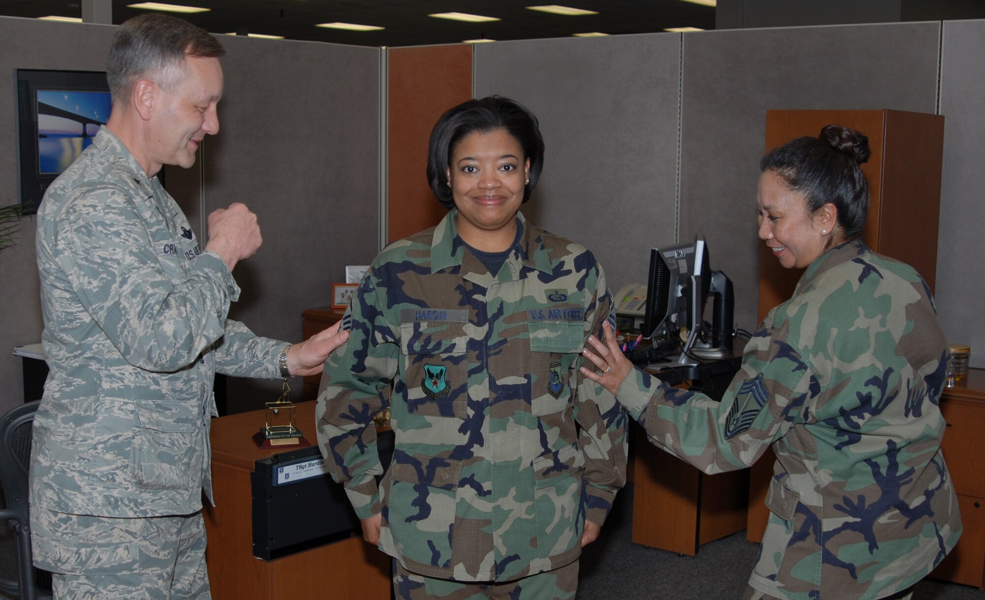 Tech. Sgt. Kenesha Hardin, DPS, is tacked by Brig. Gen. Eric Crabtree (left), ARPC commander, and Chief Master Sgt. Fatima Jones, DPS, in the contact center March 27. Sergeant Hardin is one of several ARPC Airmen who will be promoted at an official ceremony March 31. (U.S. Air Force photo/Ellen Edwards)