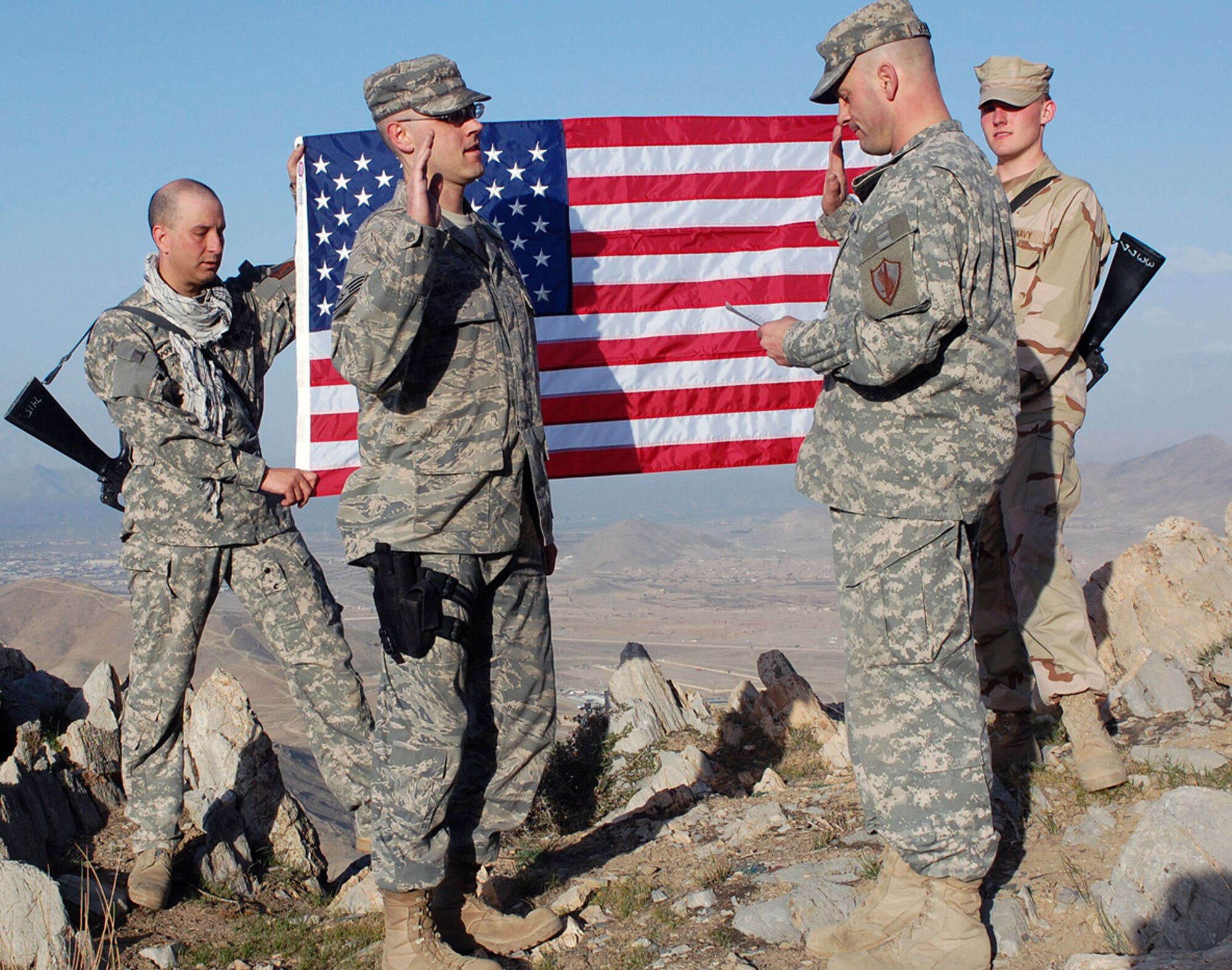 Air Force Staff Sgt. Robert Wollenberg (front left), Combined Security Transition Command-Afghanistan Public Affairs, recites the oath of enlistment read by Army Lt. Col. David Johnson (front right), CSTC-A Public Affairs, March 28 atop a mountain outside Kabul, Afghanistan. Holding the flag are Navy Petty Officer 1st Class David M. Votroubek (left) and Navy Seaman Tim Newborn (right), both CSTC-A Public Affairs. Sergeant Wollenberg is deployed from 11th Wing Public Affairs, Bolling Air Force Base, D.C. (CSTC-A photo by Marine Staff Sgt. Luis P. Valdespino Jr.)
