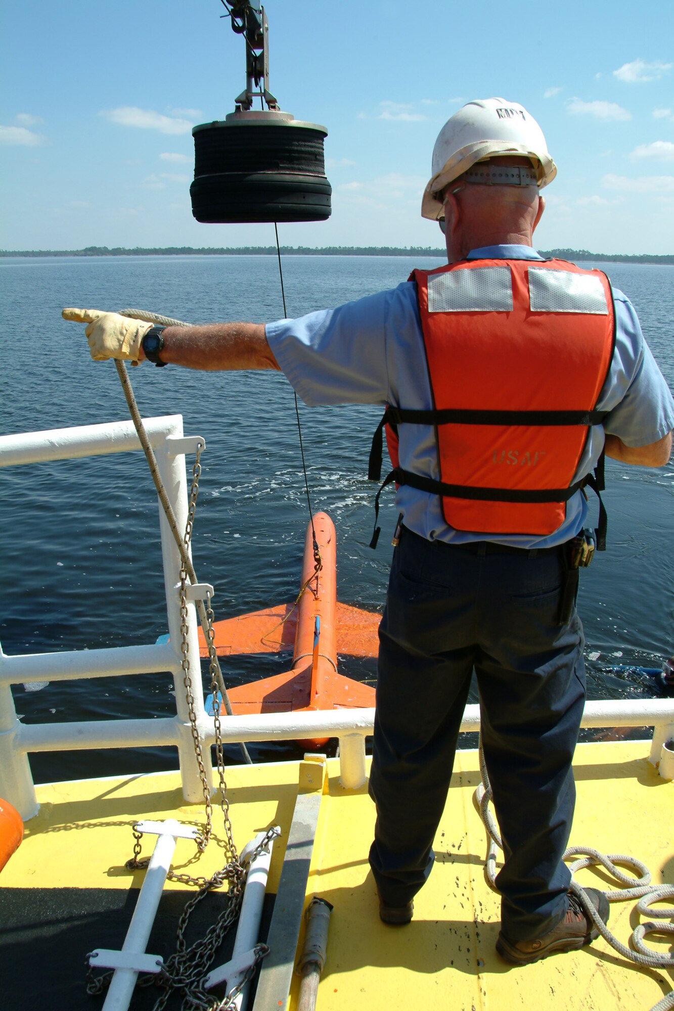 Byron Howle directs the crane movements to pick up the model BQM-107 sub-scale drone during a recovery demonstration March 26 in the waters off of Tyndall Air Force Base, Fla.  The ship used for recovery is one of only three 120-foot boats owned by the Air Force.  They are contracted from Florida Offshore through the 82nd Aerial Targets Squadron to help recover sub-scale drones after they are shot down during live fire exercises.  Photo by Staff Sgt. Samuel King Jr.