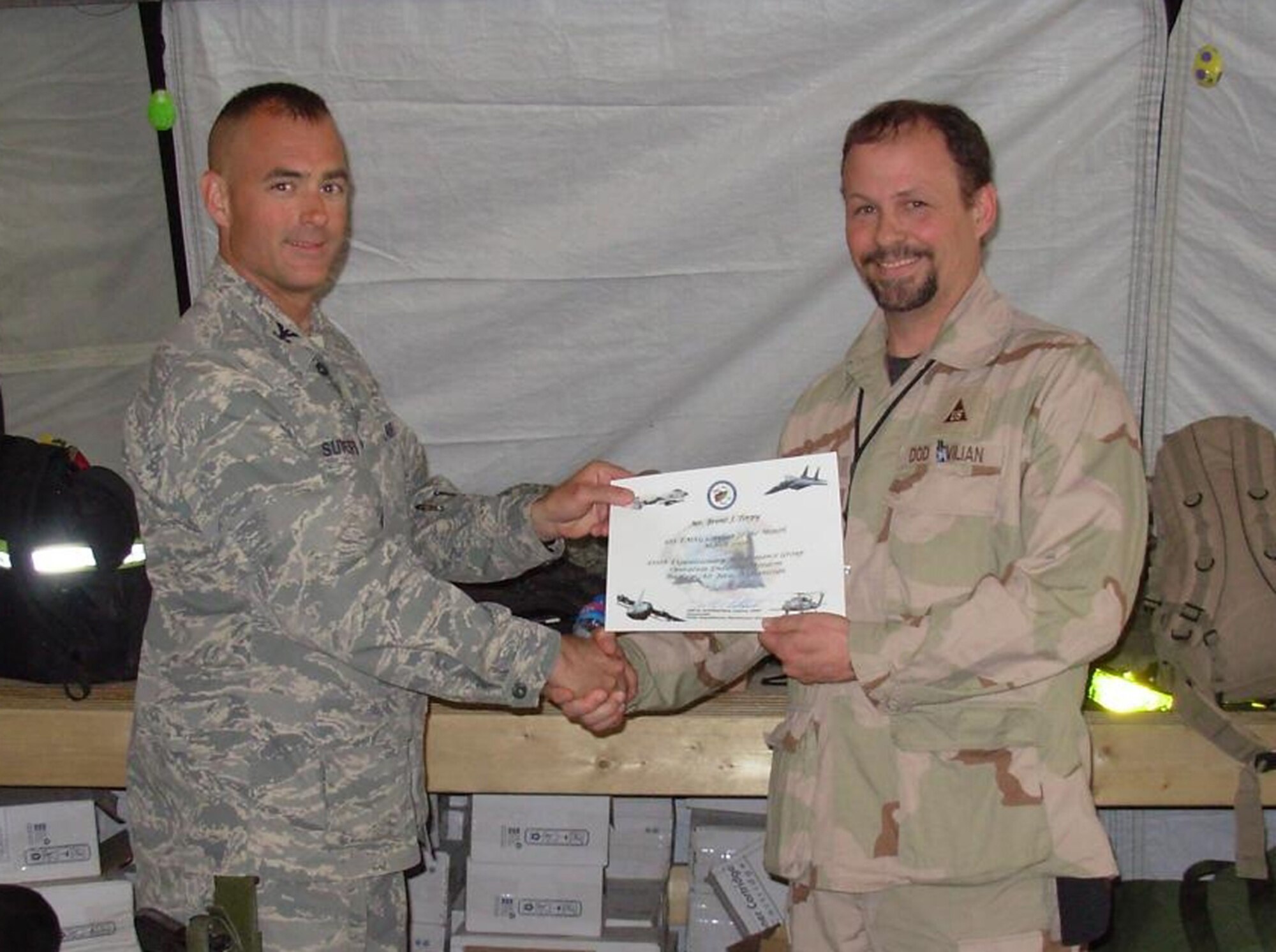 BAGRAM AIR BASE, Afghanistan -- Col. Jon Sutterfield, 455th Expeditionary Maintenance Group commander, presents Brent Torphy, 455th Expeditionary Aircraft Maintenance Unit, a certificate for being named the 455th Air Expeditionary Wing civilian of the month. Mr. Torphy is deployed from Spangdahlem Air Base, Germany. (U.S. Air Force photo)