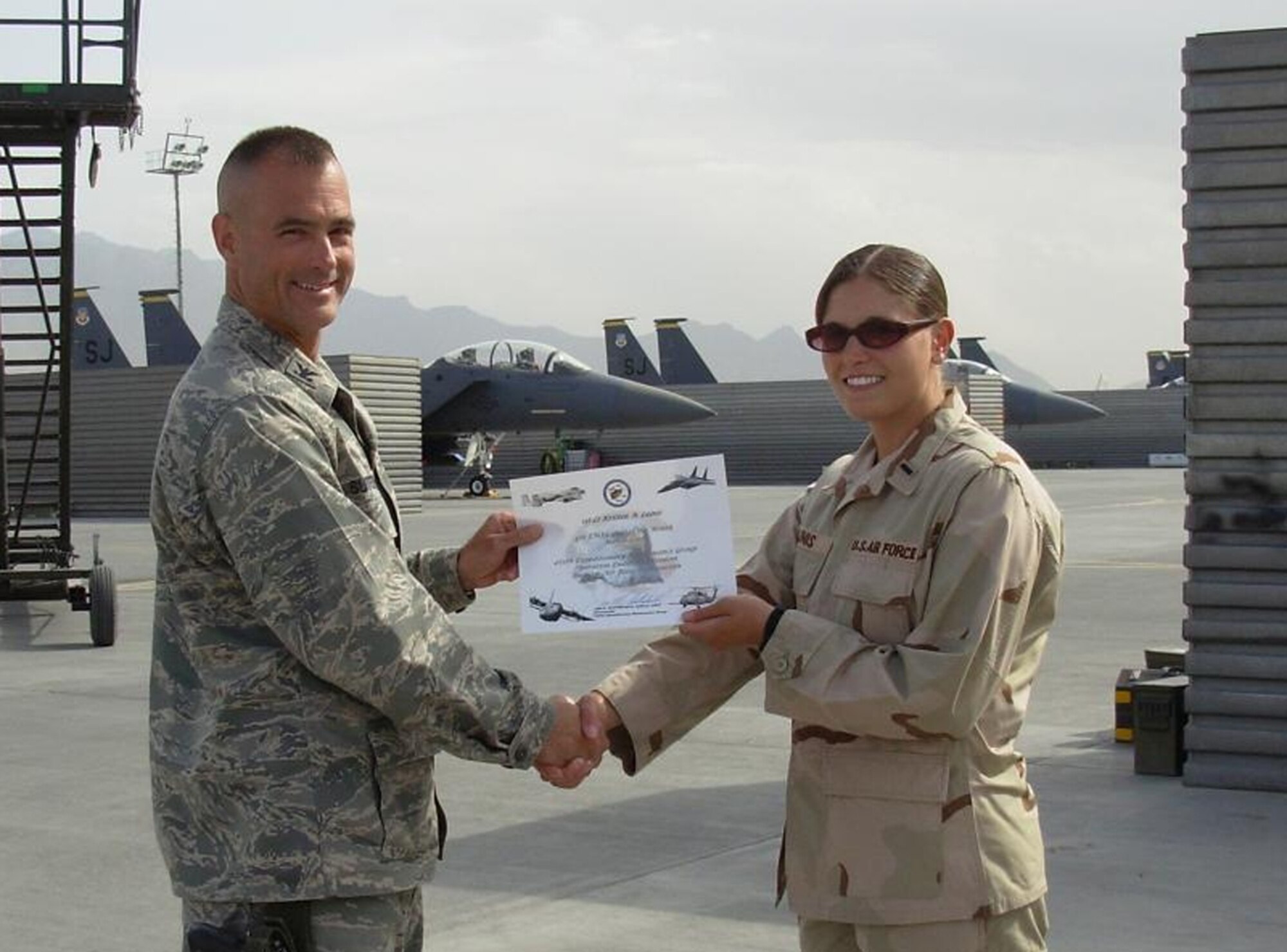 BAGRAM AIR BASE, Afghanistan -- Col. Jon Sutterfield, 455th Expeditionary Maintenance Group commander, presents 1st Lt. Kristen Lainis, 455th Expeditionary Aircraft Maintenance Unit, a certificate for being named the 455th Air Expeditionary Wing company grade officer of the month. Lieutenant Lainis is deployed from Spangdahlem Air Base, Germany. (U.S. Air Force photo)